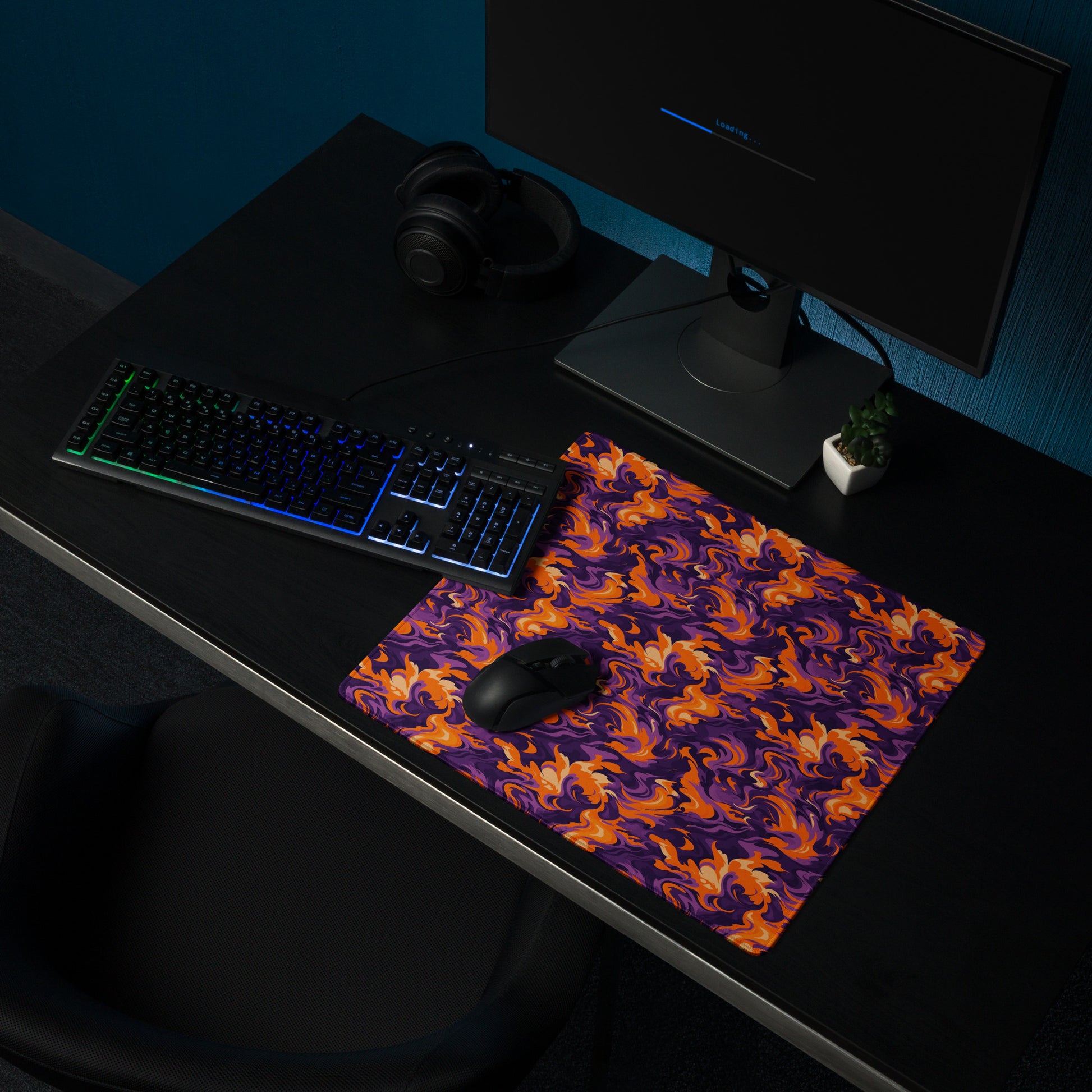 A 18" x 16" desk pad with a purple and orange camo pattern sitting on a desk.
