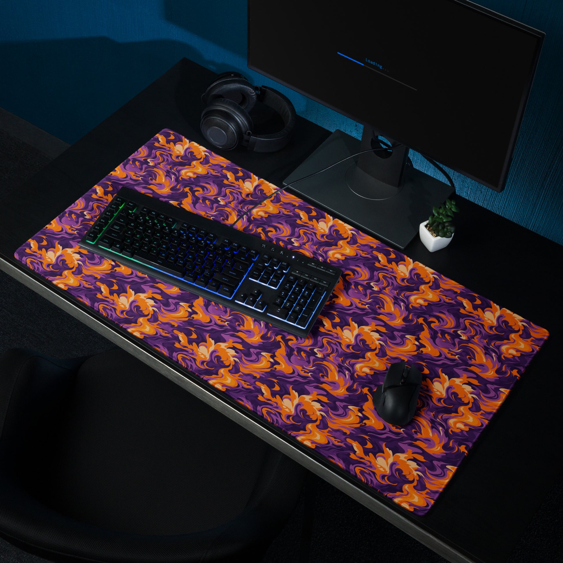 A 36" x 18" desk pad with a purple and orange camo pattern sitting on a desk.