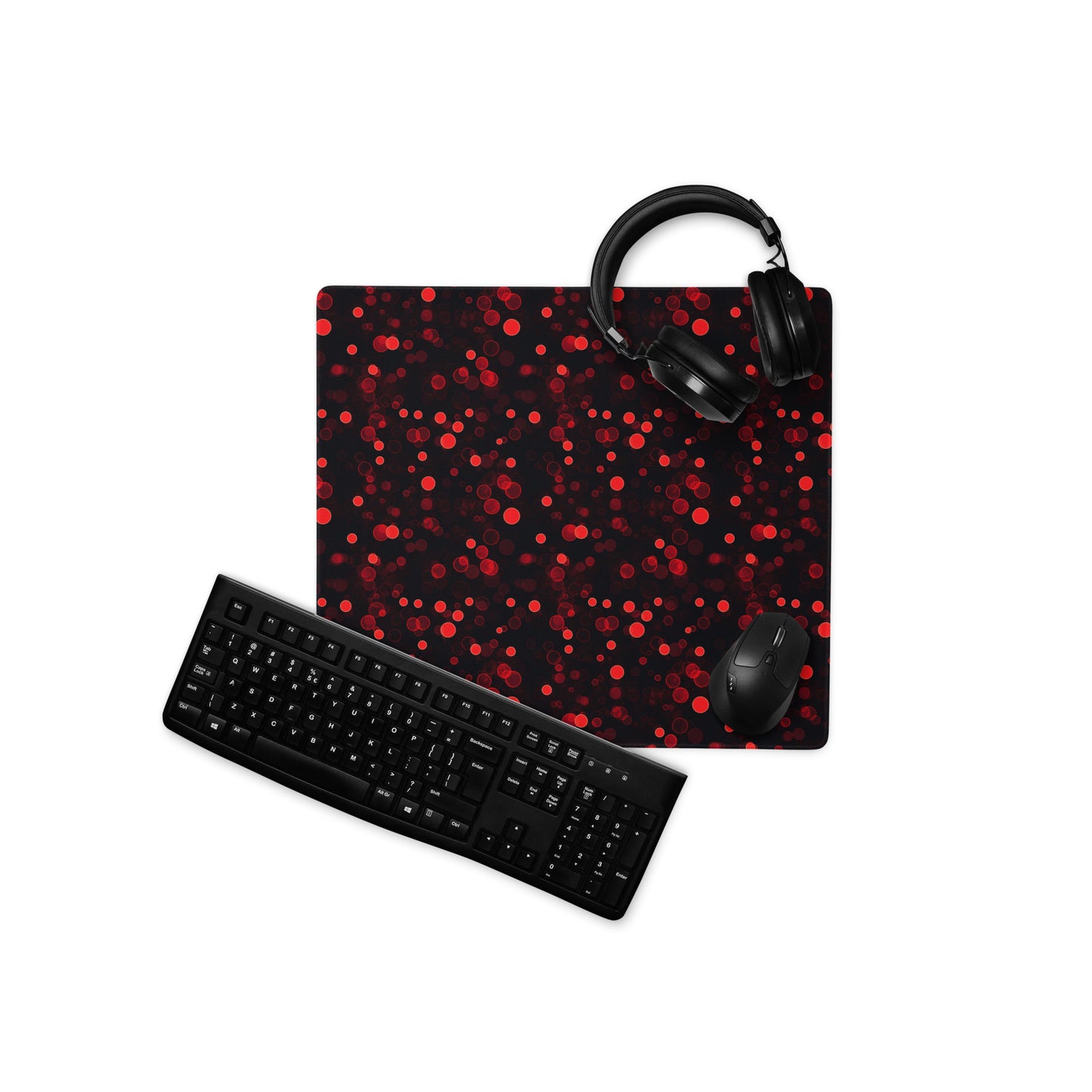 A 18" x 16" desk pad with red polka dots. With a keyboard, mouse, and headphones sitting on it.