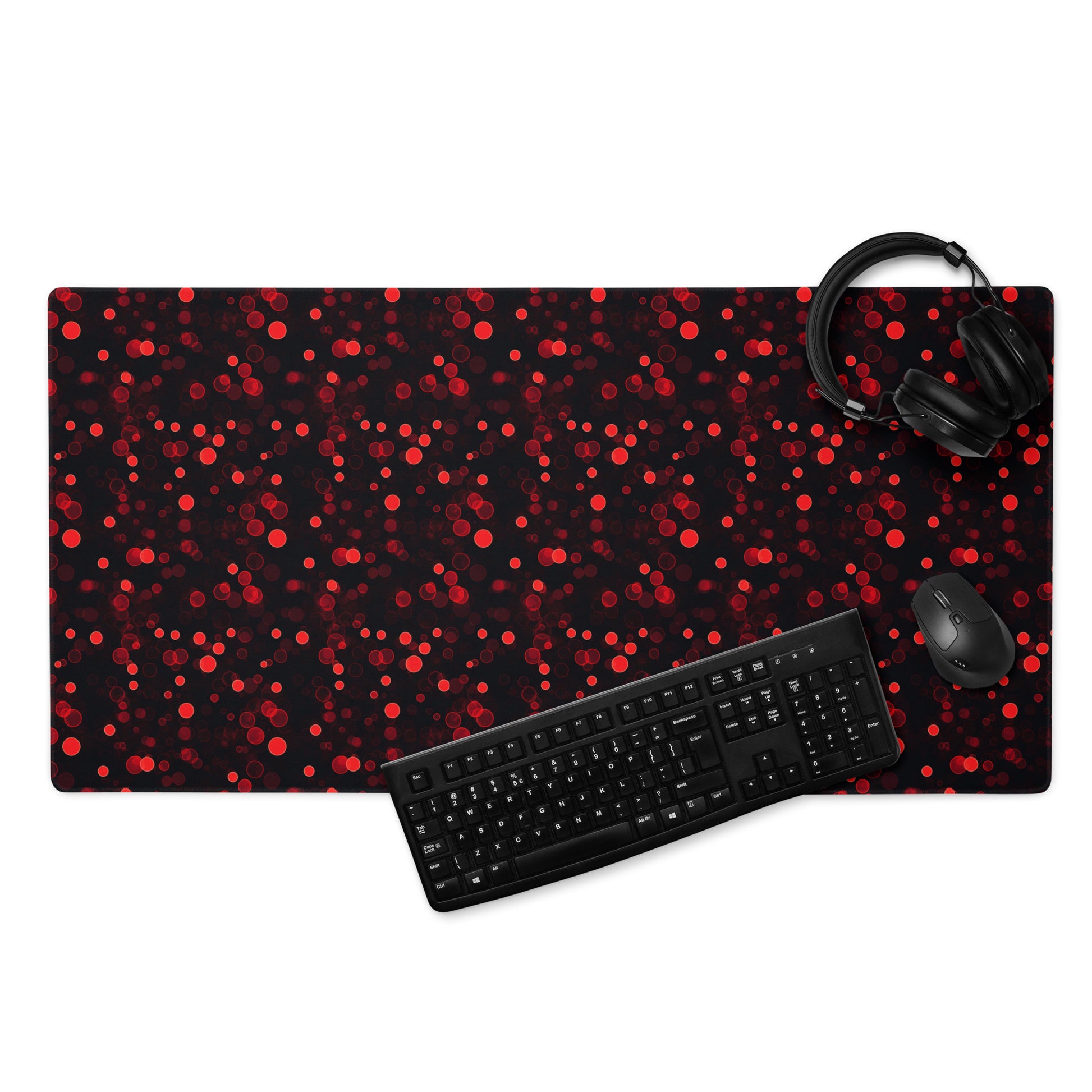 A 36" x 18" desk pad with red polka dots. With a keyboard, mouse, and headphones sitting on it.