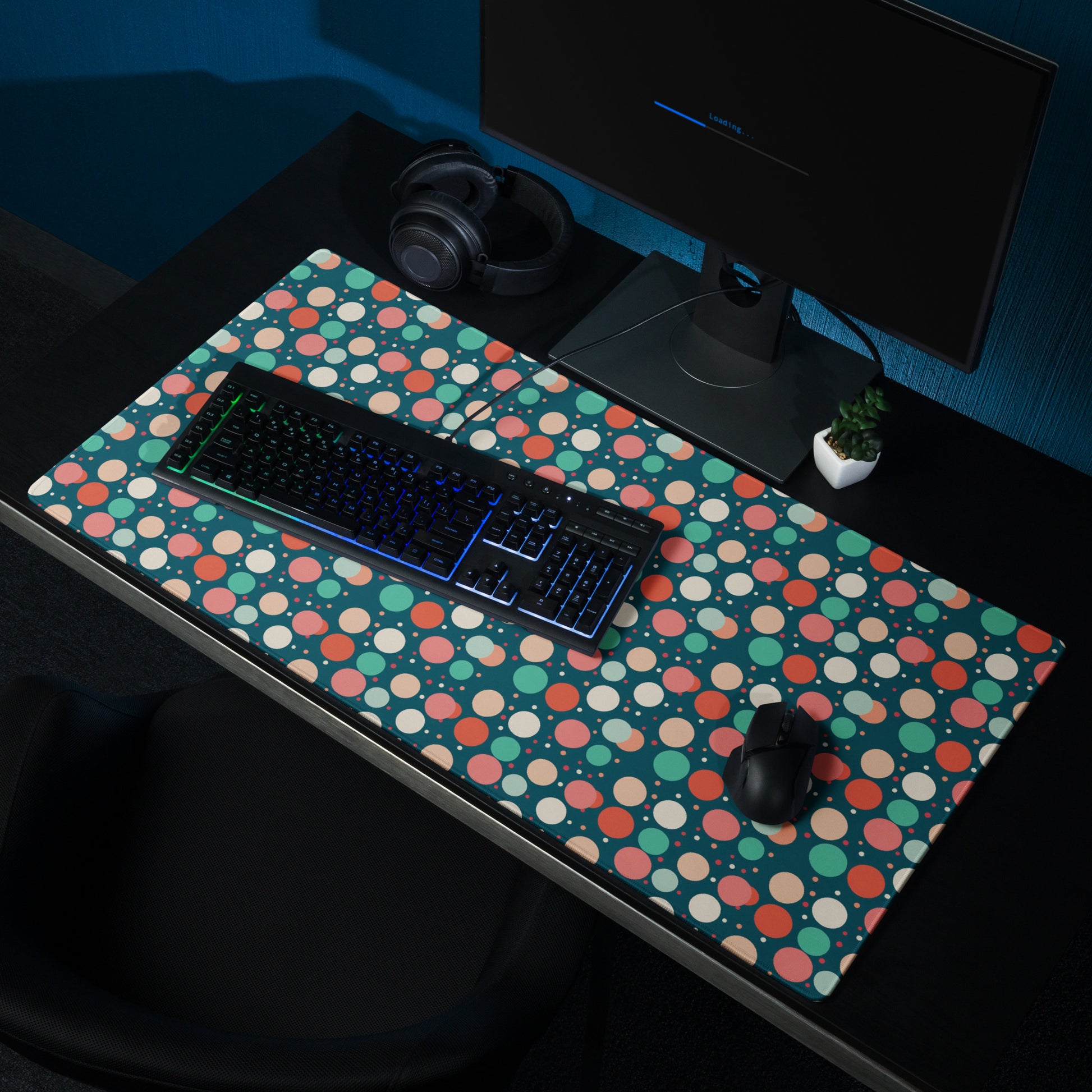 A 36" x 18" desk pad with red teal and yellow polka dot pattern sitting on a desk.