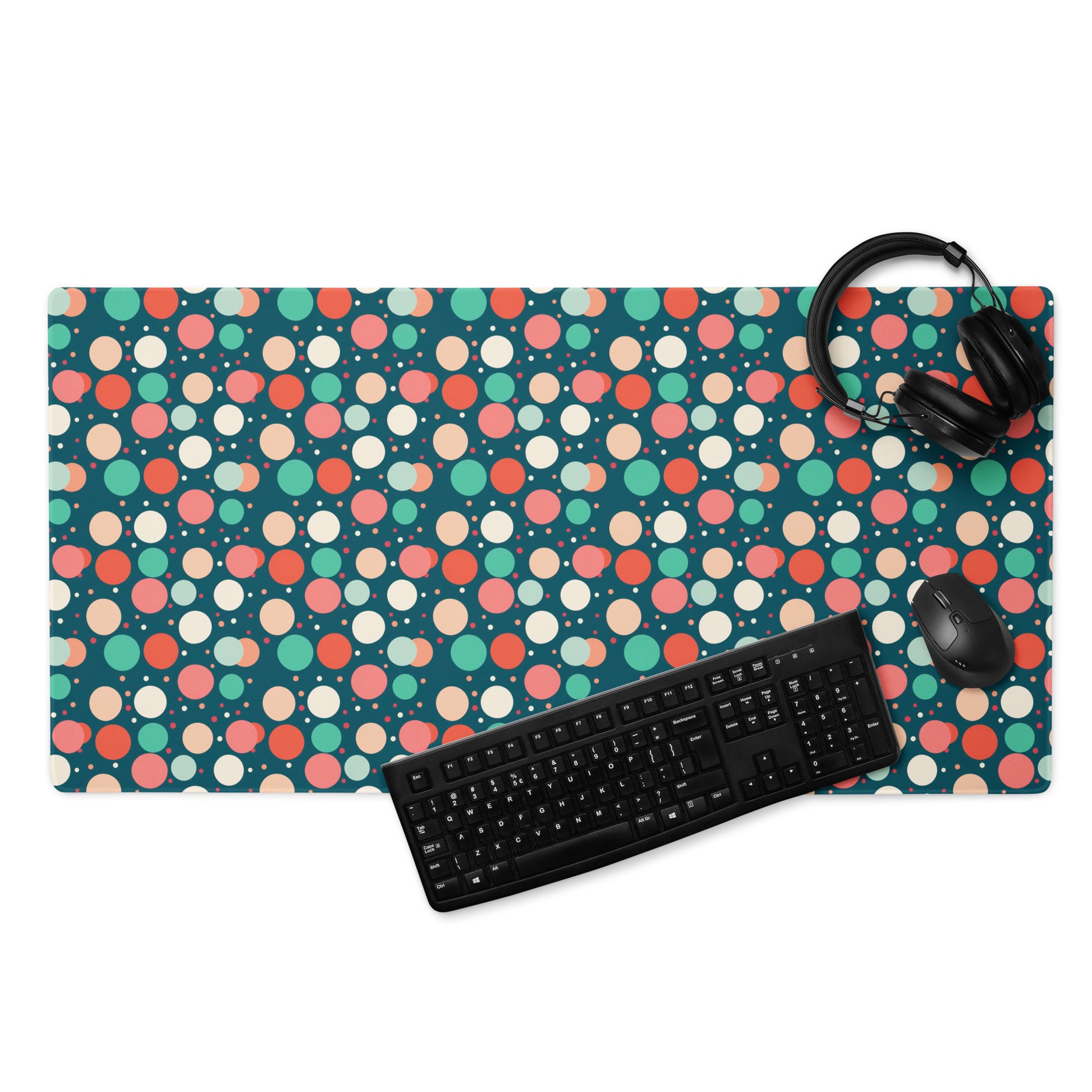  A 36" x 18" desk pad with red teal and yellow polka dot pattern. With a keyboard, mouse, and headphones sitting on it.