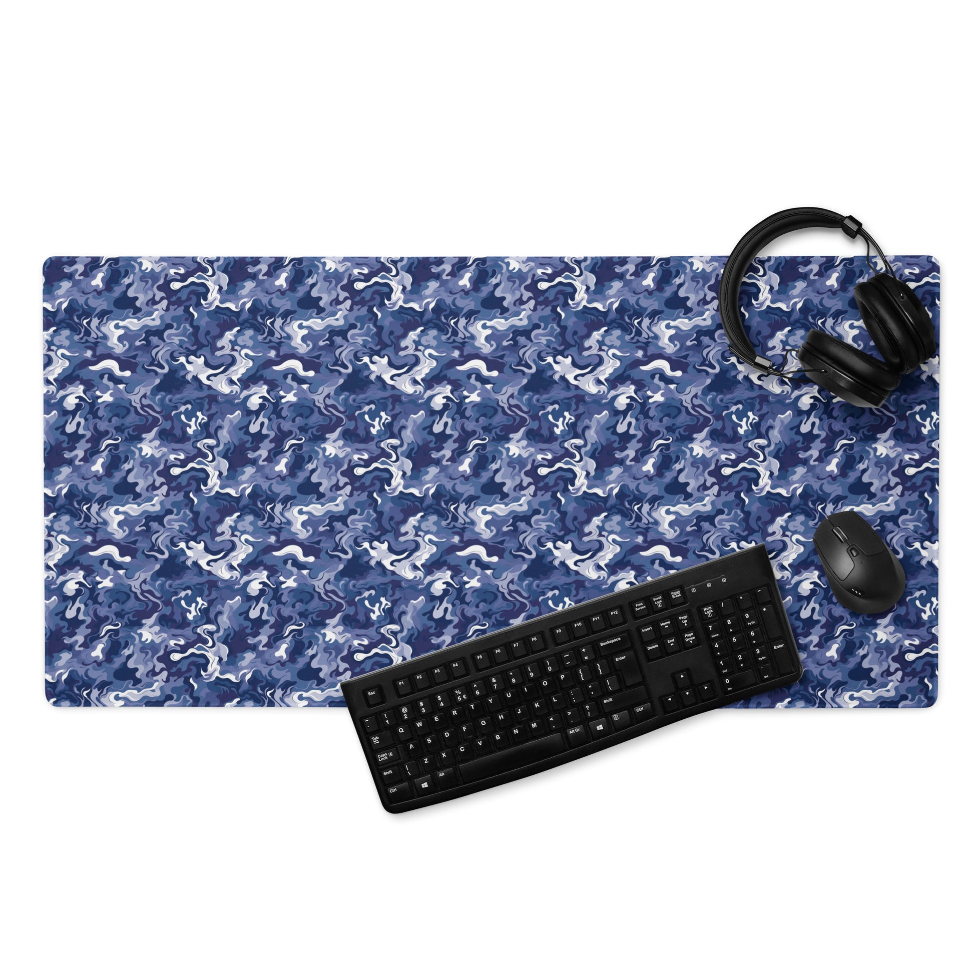 A 36" x 18" desk pad with a royal blue and white camo pattern. With a keyboard, mouse, and headphones sitting on it.