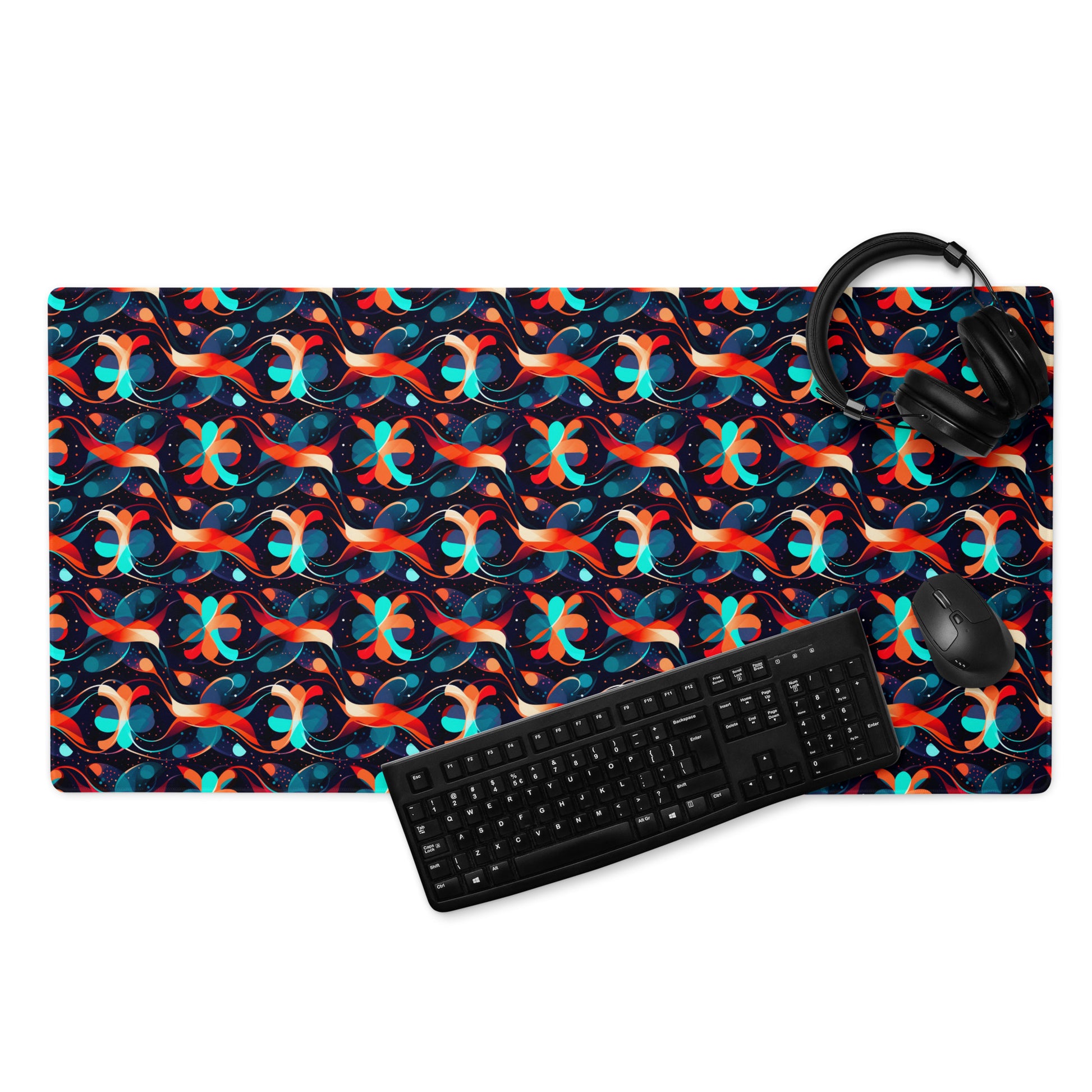 A 36" x 18" desk pad with a wavy orange and blue pattern. With a keyboard, mouse, and headphones sitting on it.