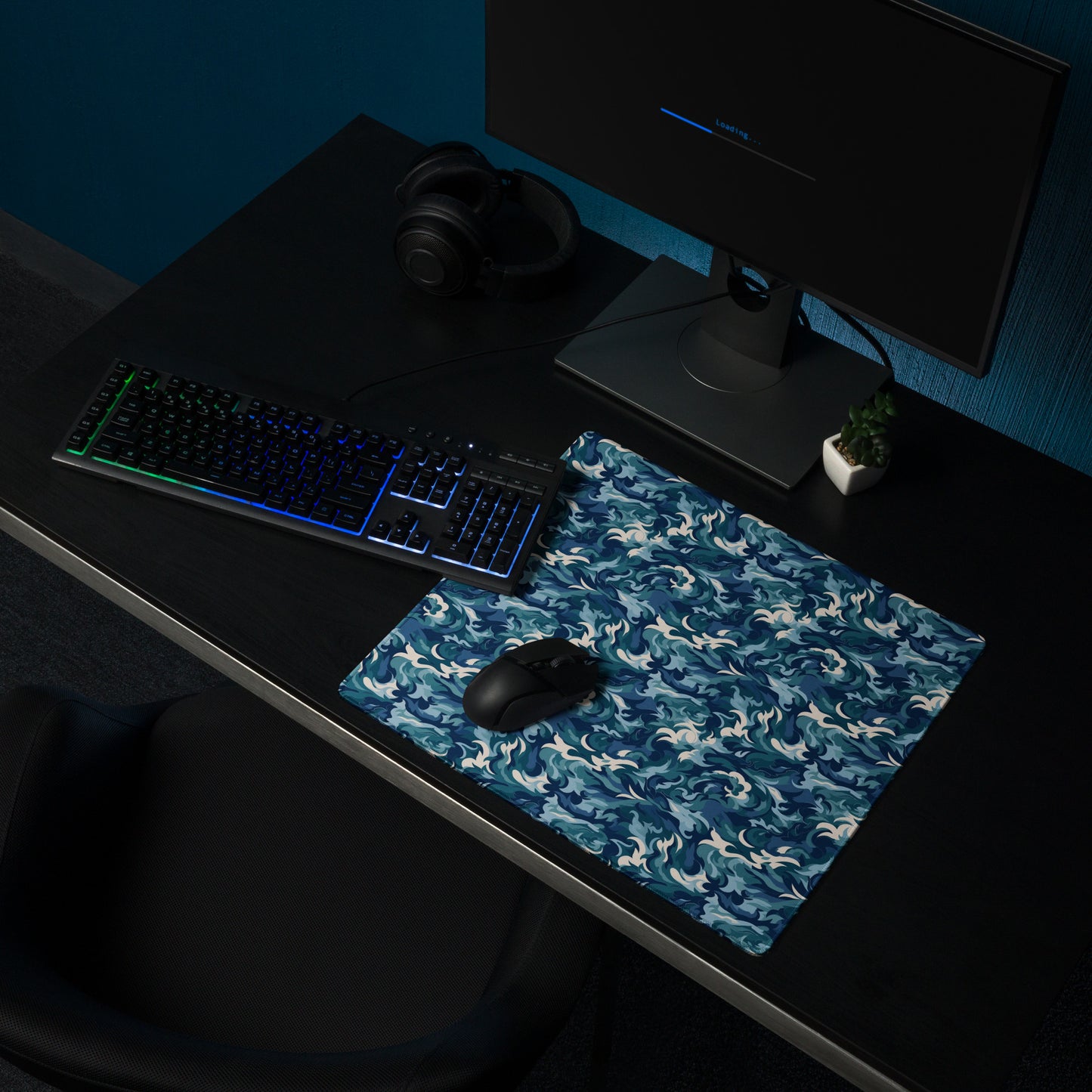 A 18" x 16" desk pad with a teal and white camo pattern sitting on a desk.