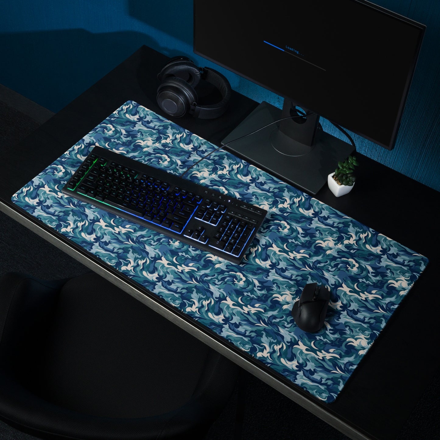 A 36" x 18" desk pad with a teal and white camo pattern sitting on a desk.