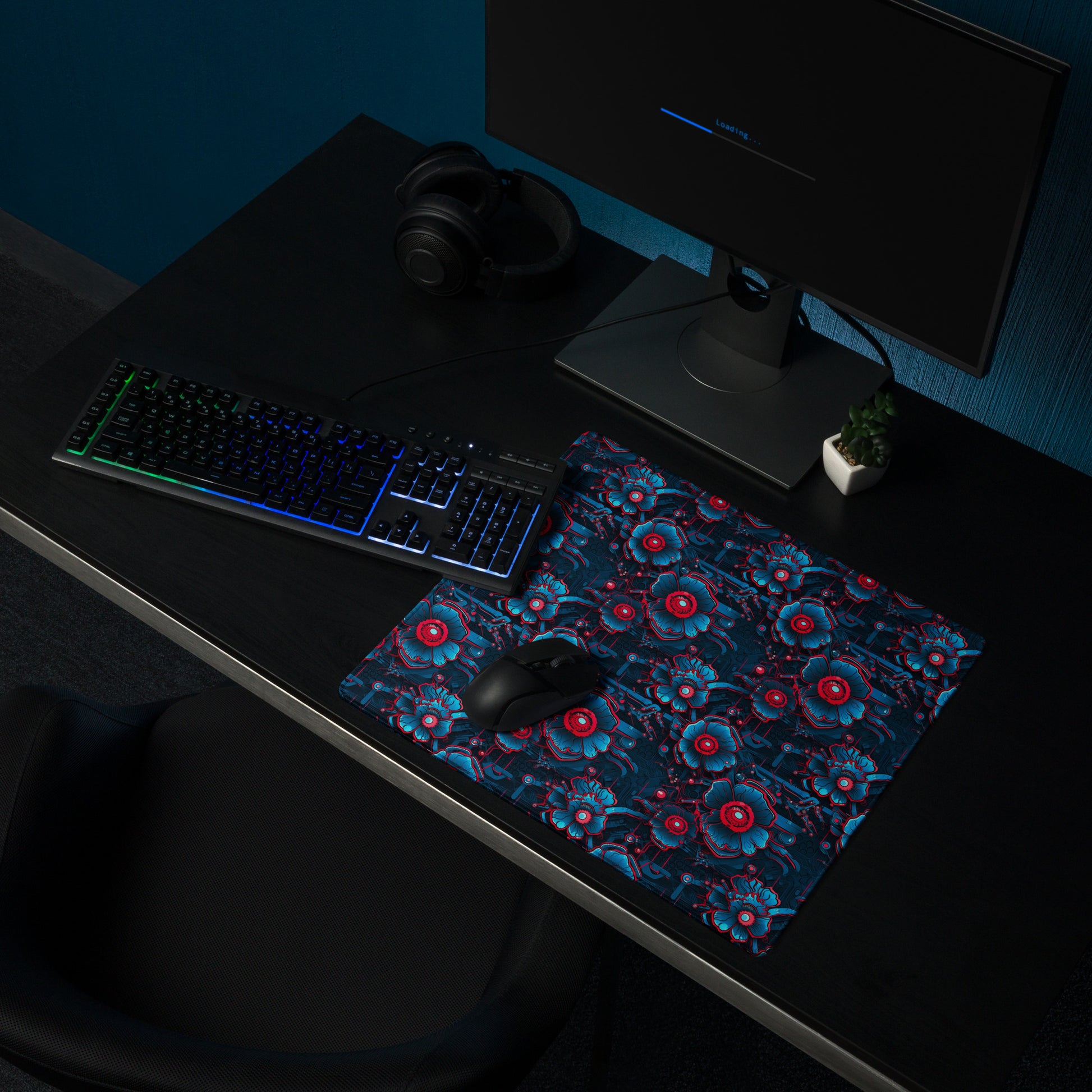 A 18" x 16" desk pad with a blue and red robotic floral pattern sitting on a desk.