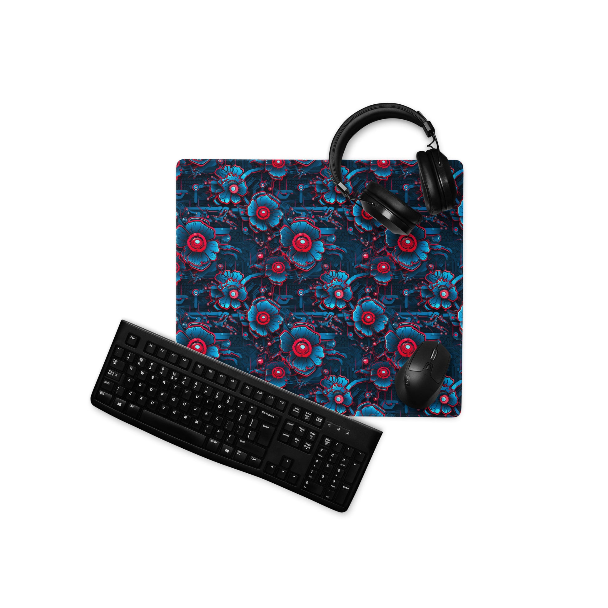 A 18" x 16" desk pad with a blue and red robotic floral pattern. With a keyboard, mouse, and headphones sitting on it.