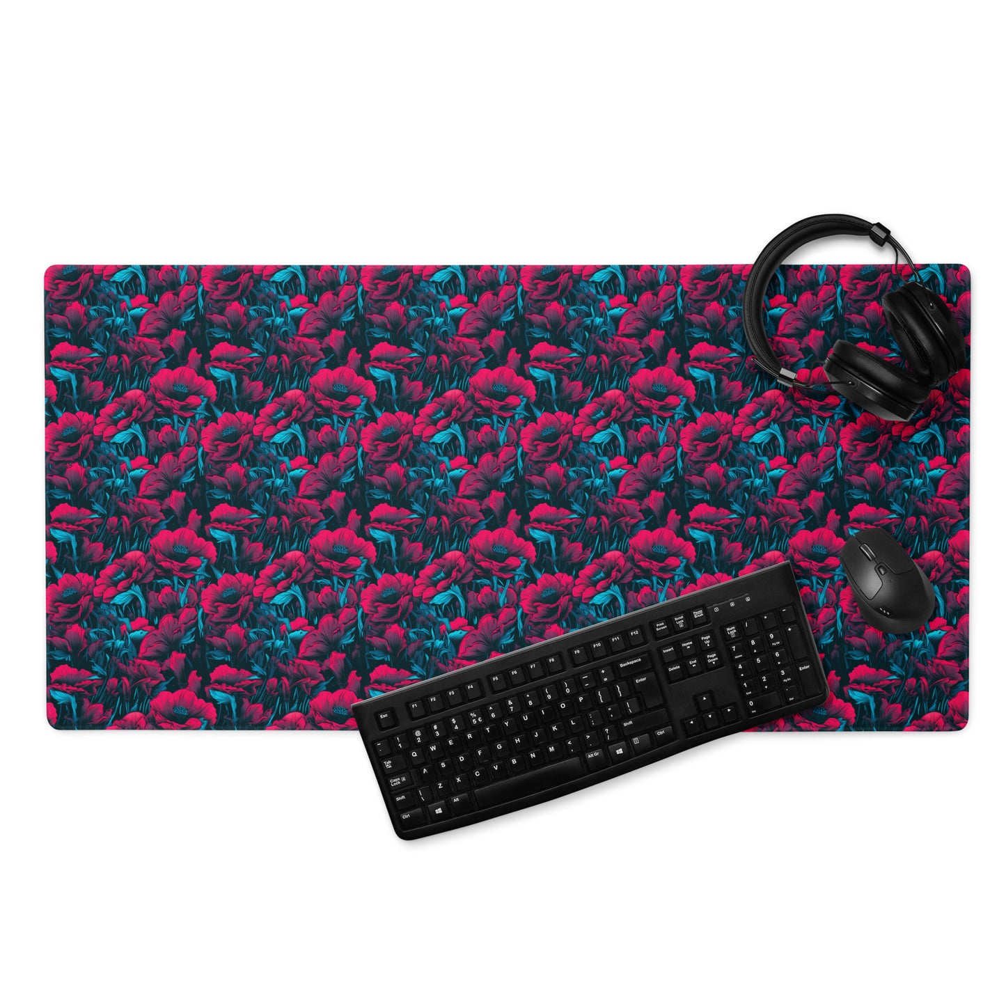 A 36" x 18" desk pad with a red and blue floral pattern. With a keyboard, mouse, and headphones sitting on it.