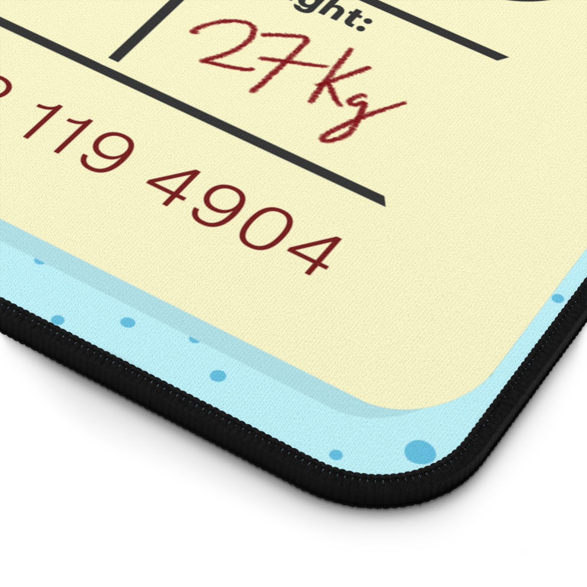 The corner of a 12" x 18" desk mat with a dotted blue background and a blue and yellow Tokyo airline baggage tag on it.