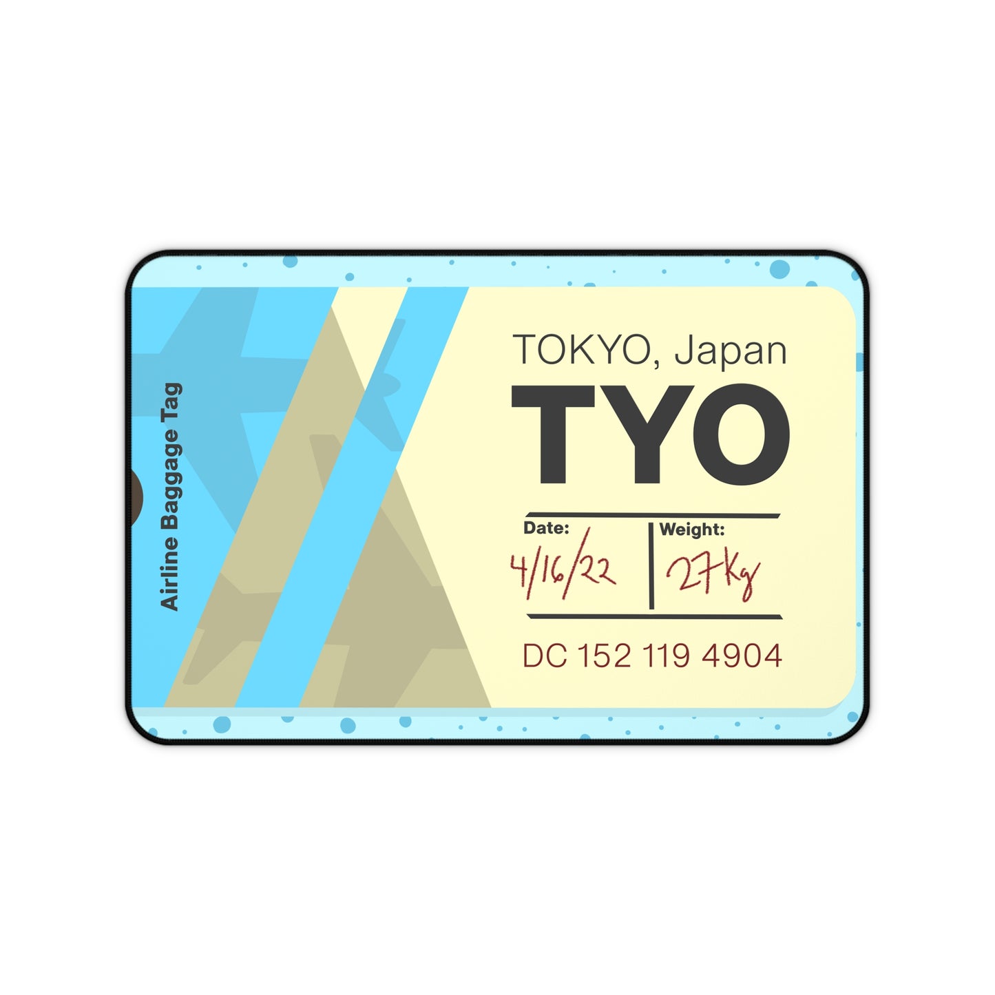 A 12" x 18" desk mat with a dotted blue background and a blue and yellow Tokyo airline baggage tag on it.