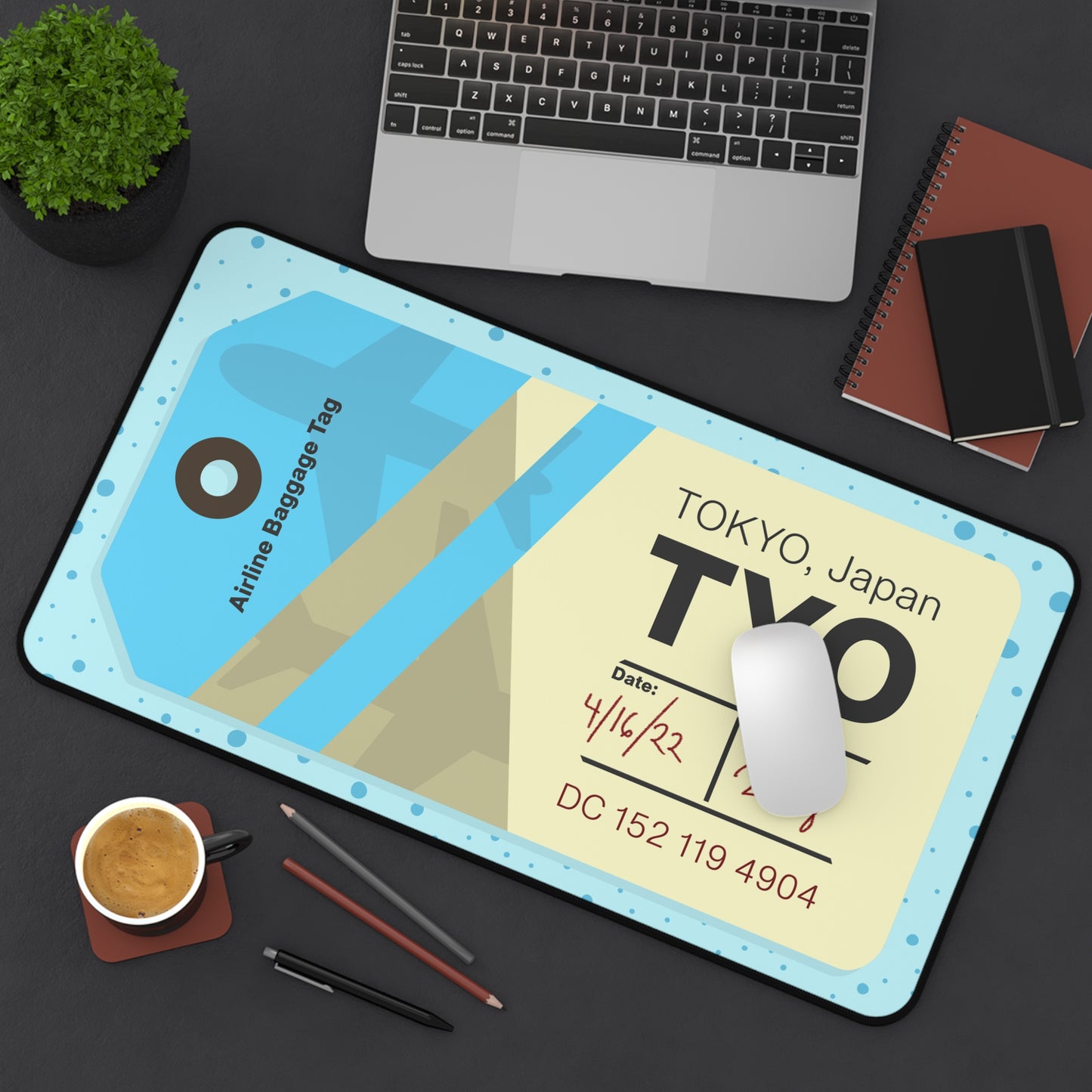 A 12" x 22" desk mat with a dotted blue background and a blue and yellow Tokyo airline baggage tag on it sitting at an angle.