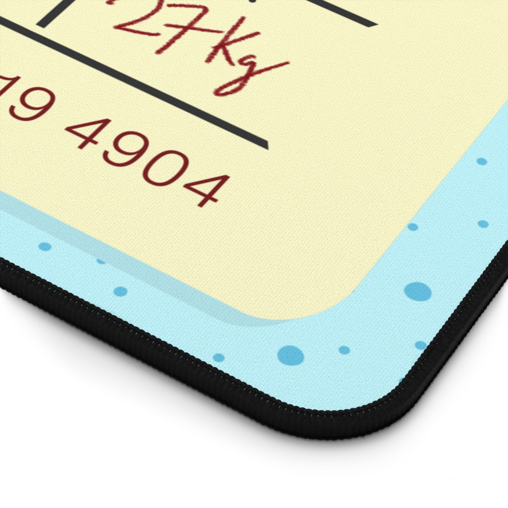 The corner of a 12" x 22" desk mat with a dotted blue background and a blue and yellow Tokyo airline baggage tag on it.
