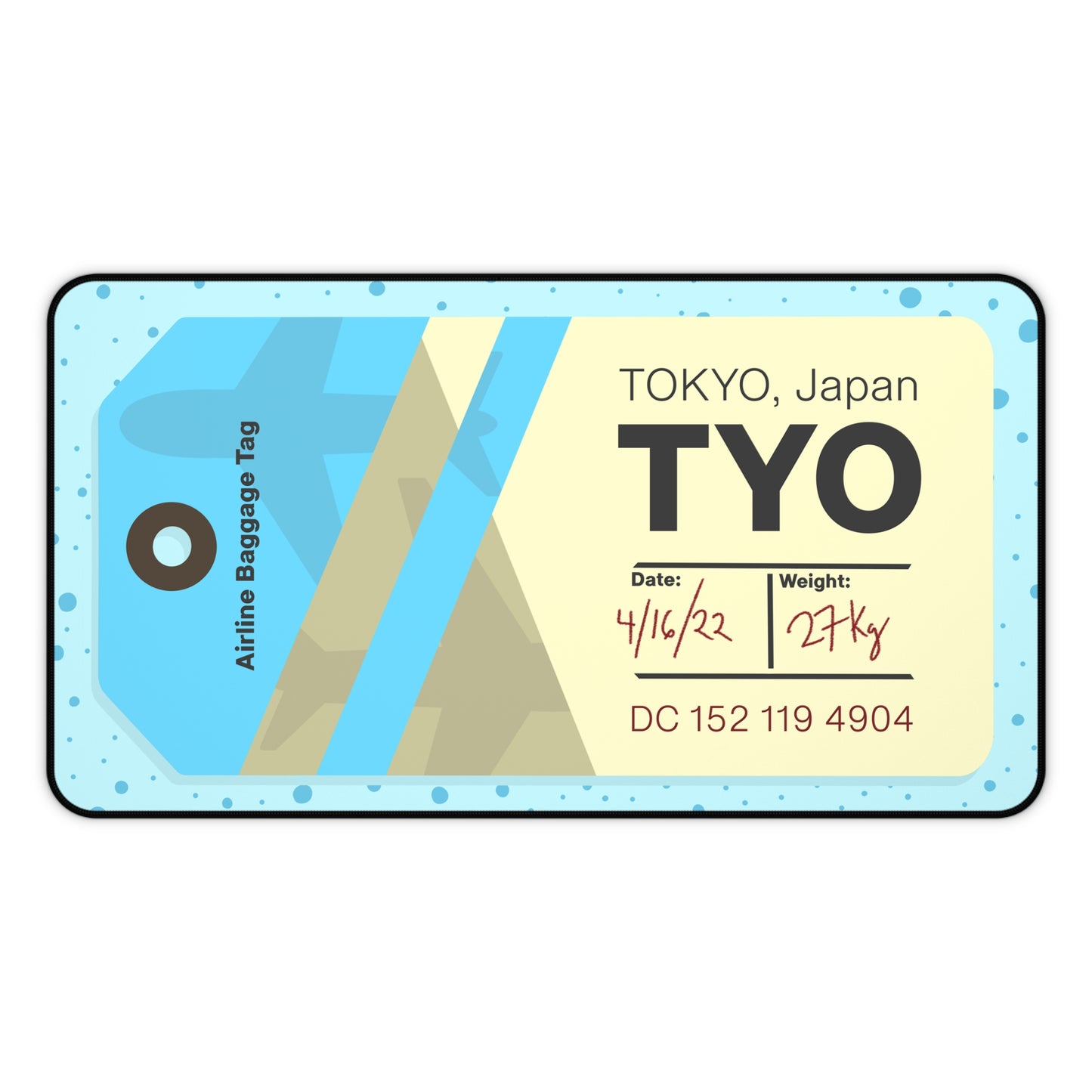 A 12" x 22" desk mat with a dotted blue background and a blue and yellow Tokyo airline baggage tag on it.