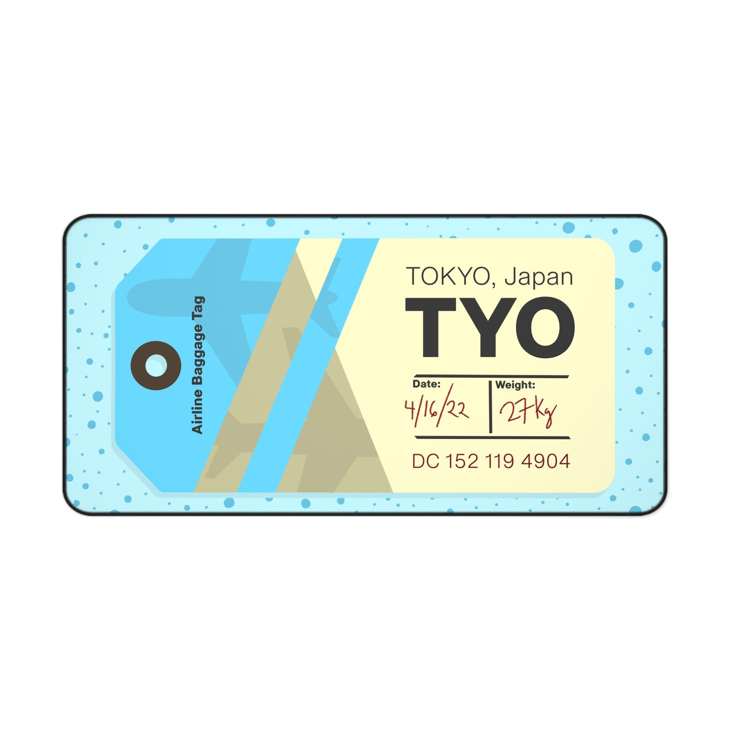 A 31" x 15.5" desk mat with a dotted blue background and a blue and yellow Tokyo airline baggage tag on it.
