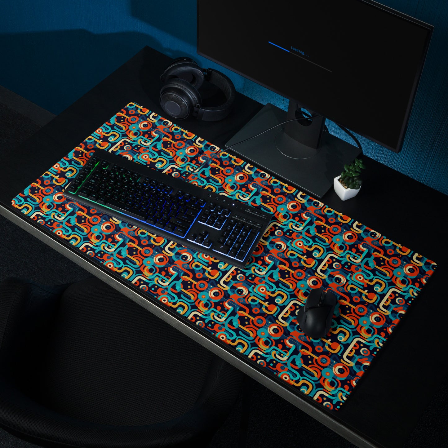 A 36" x 18" gaming desk pad with blue, orange, and beige lines on a black background. It sits on a black desk with a keyboard, monitor, and mouse.