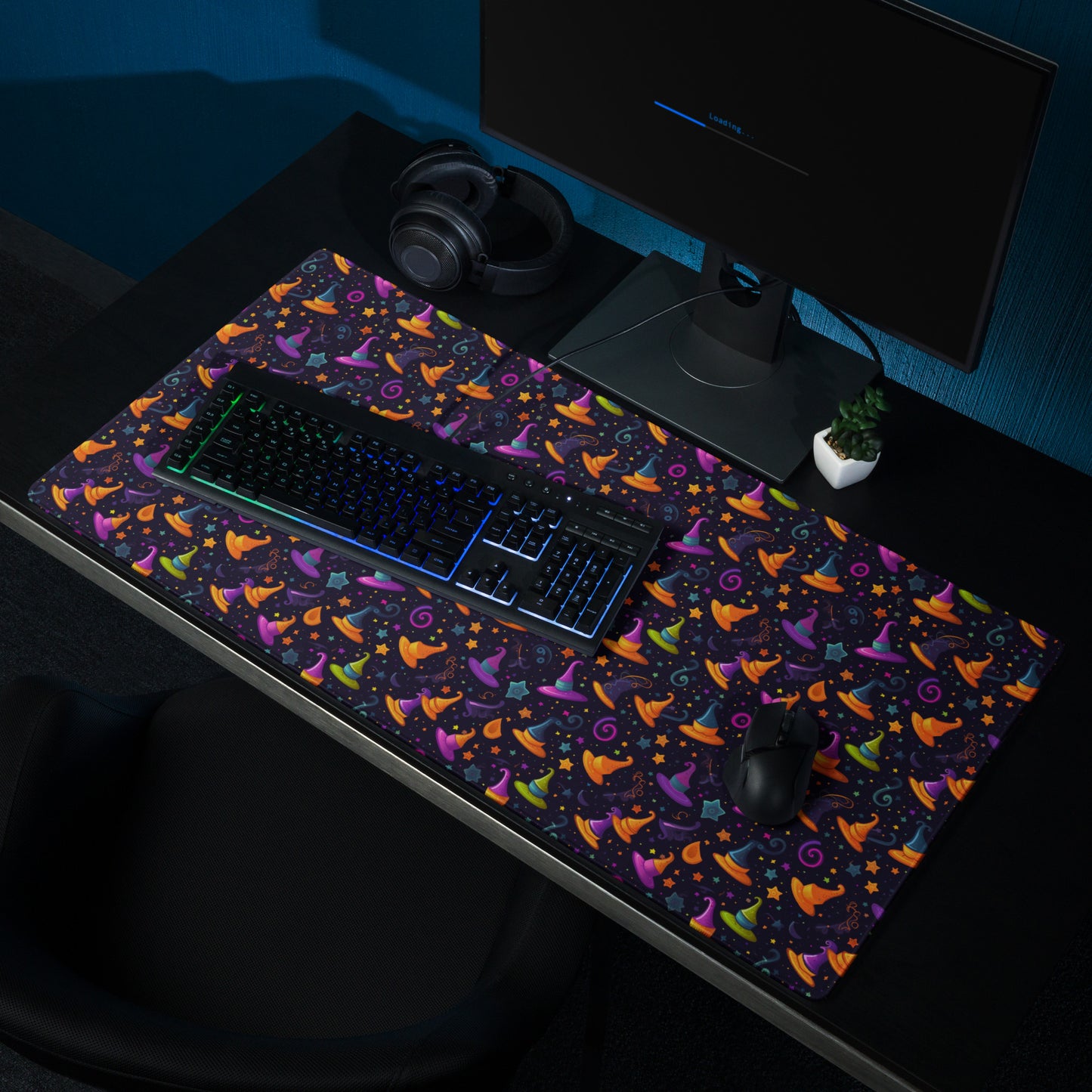 A 36" x 18" desk pad with a orange and purple wizard hat pattern sitting on a desk.