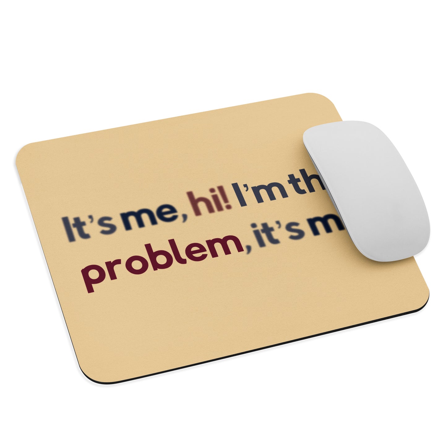 A beige mouse pad with the quote It's me, hi! I'm the problem, it's me. A mouse sits on the mouse pad.