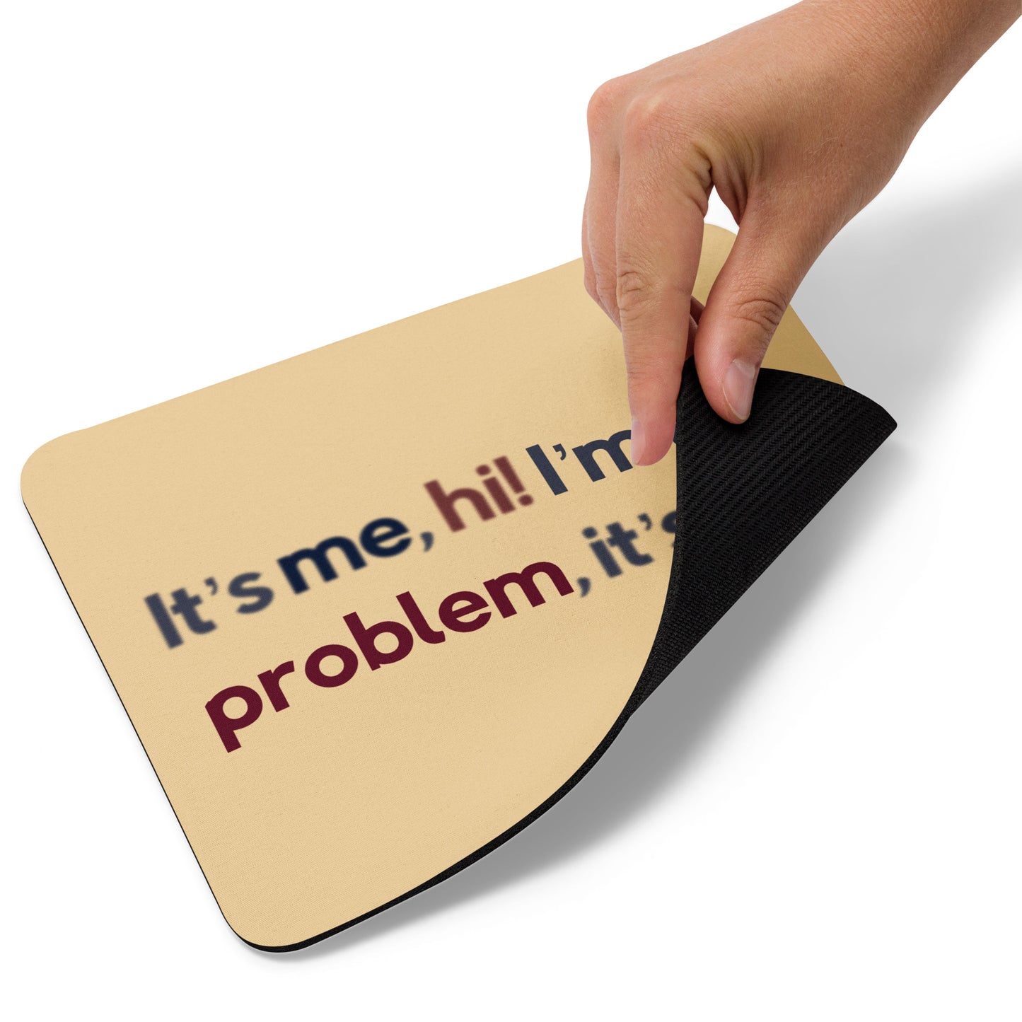 A beige mouse pad with the quote It's me, hi! I'm the problem, it's me. The bottom right corner is lifted up.