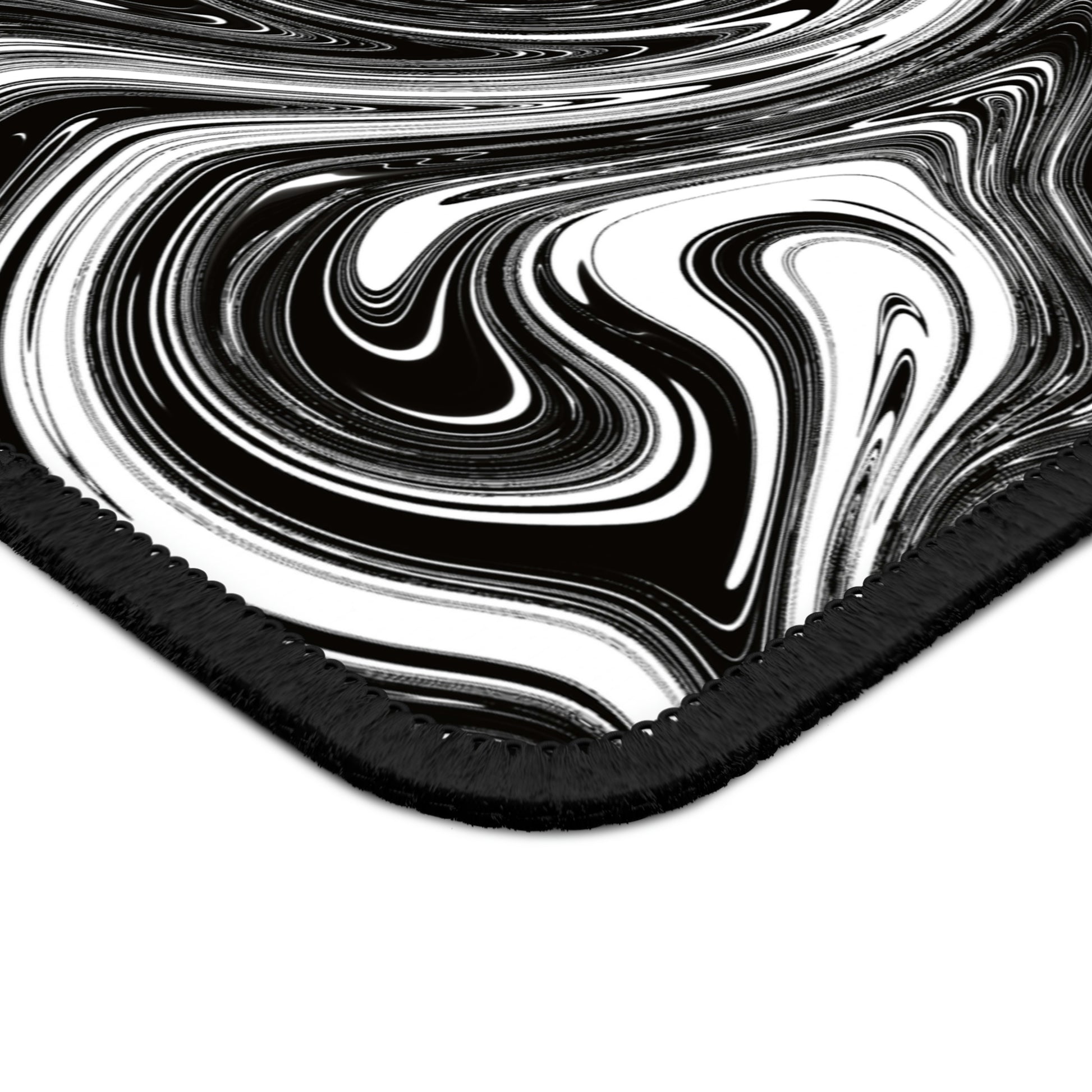 The corner of a gaming mouse pad with black and white swirls.