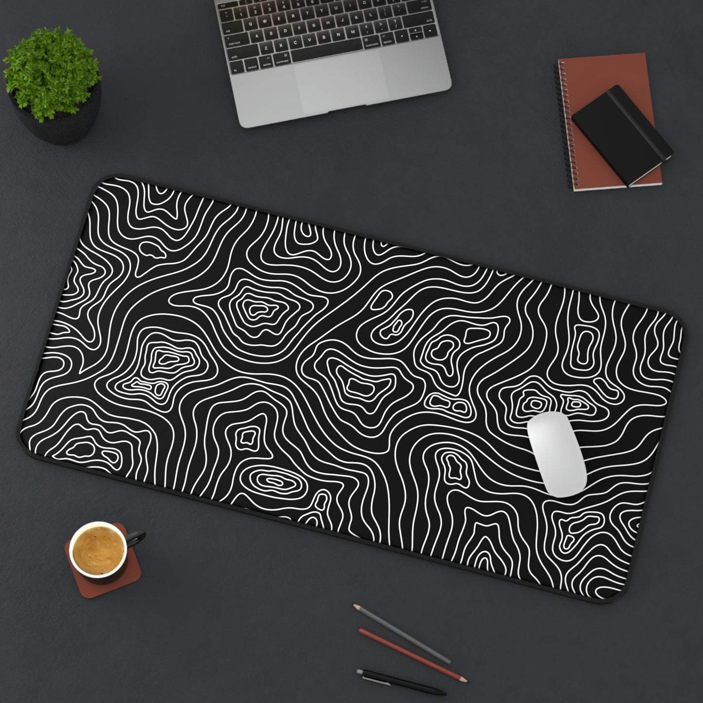 A 31" x 15.5" black desk mat with white topographic lines sitting at an angle. A mouse sits on top of it.