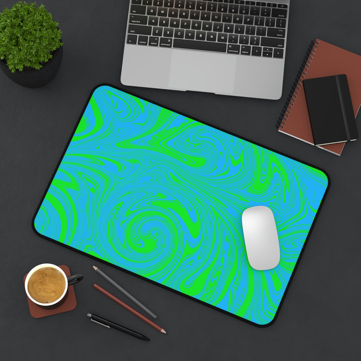 A 12" x 18" desk mat with blue and green swirls sitting at an angle.