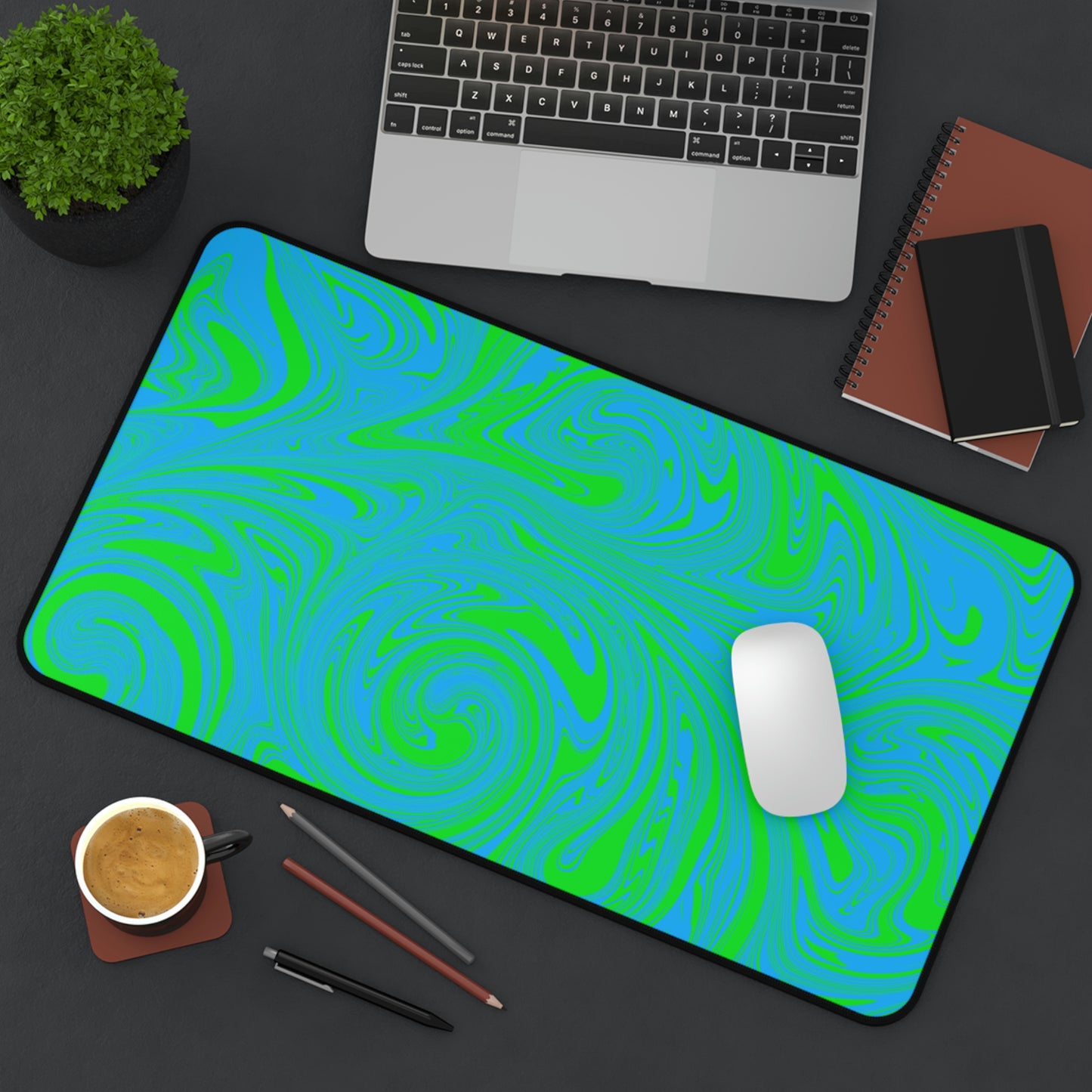 A 12" x 22" desk mat with blue and green swirls sitting at an angle.