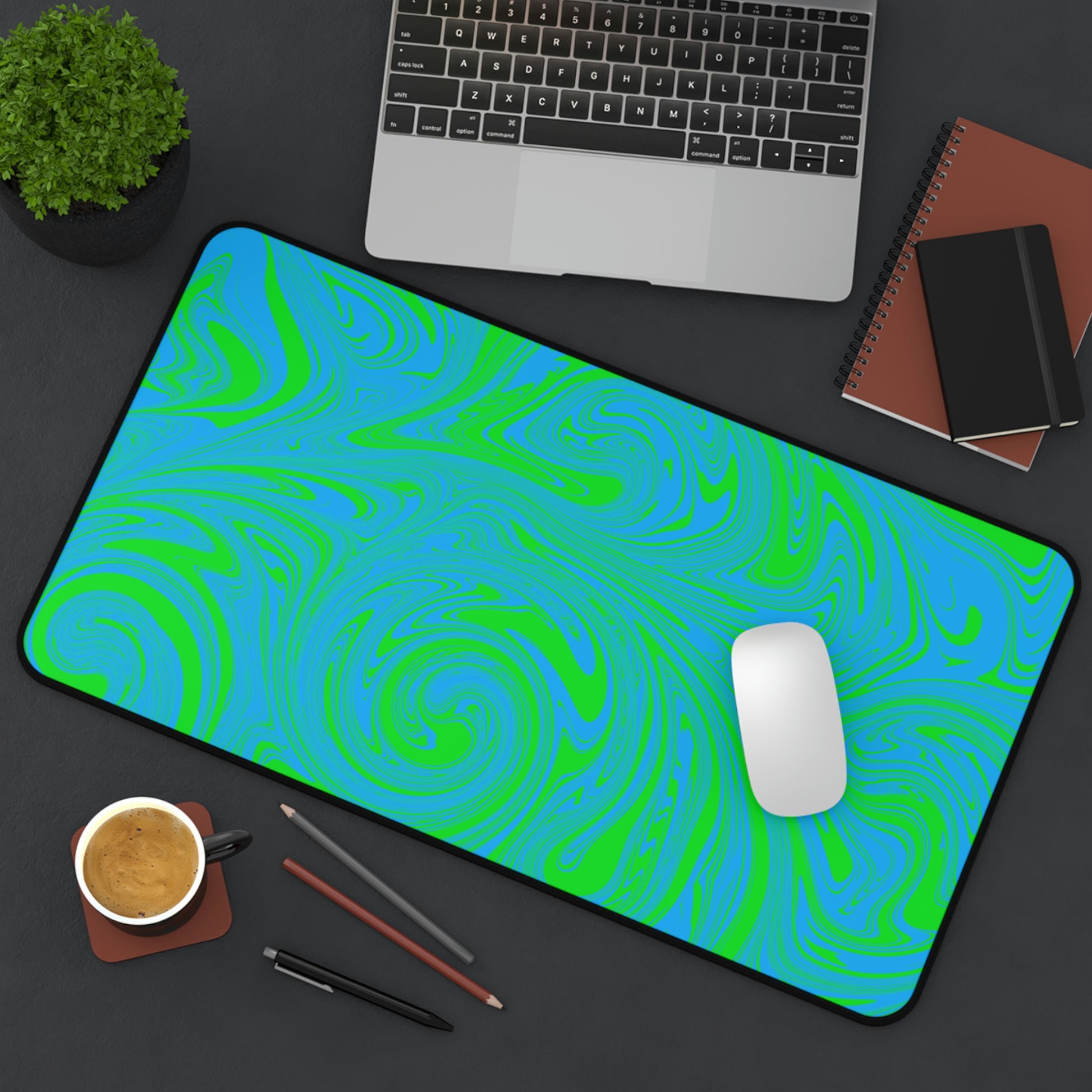 A 12" x 22" desk mat with blue and green swirls sitting at an angle.