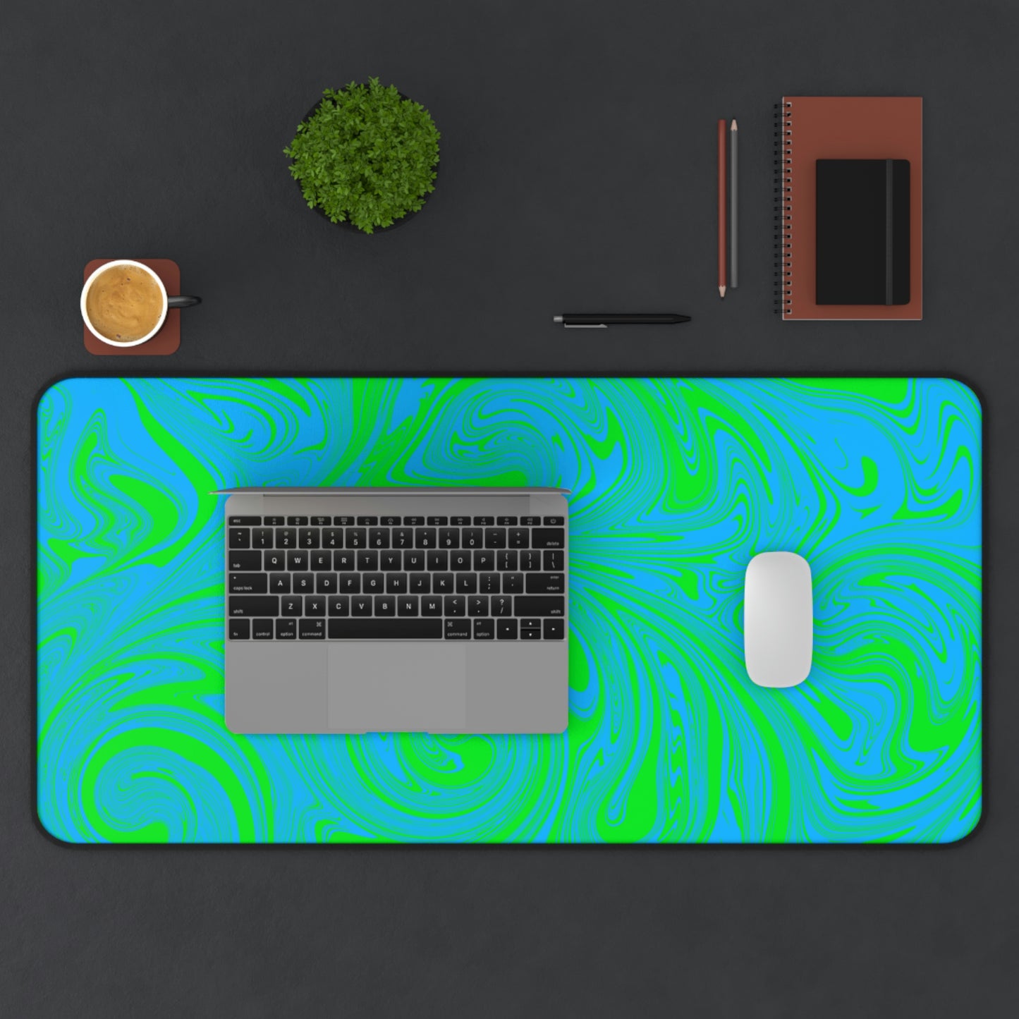 A 31" x 15.5" desk mat with blue and green swirls. A laptop and mouse sit on top of it.