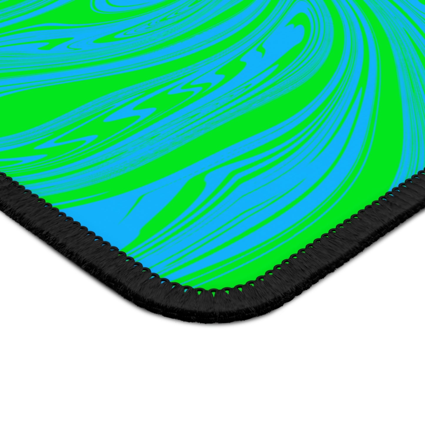 The corner of a gaming mouse pad with blue and green swirls.