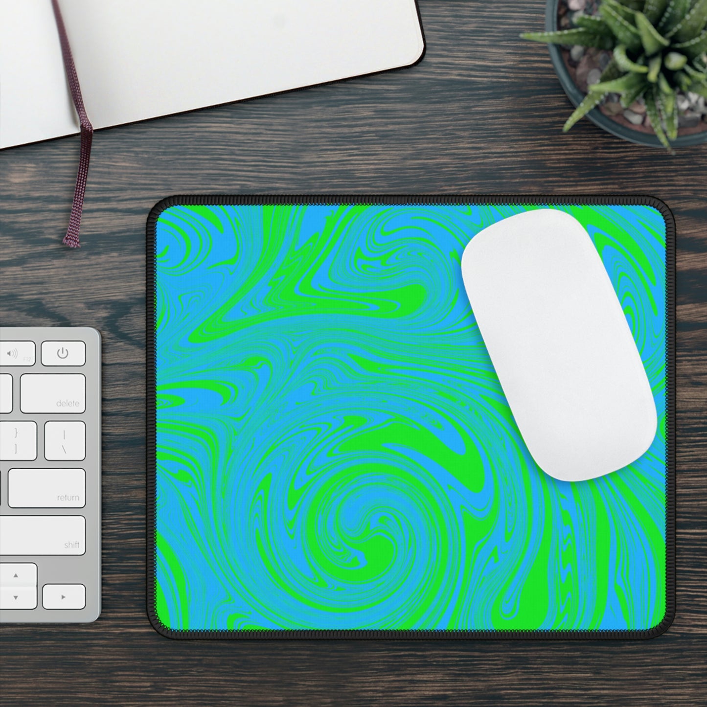 A gaming mouse pad with blue and green swirls. A mouse sits on top of it.