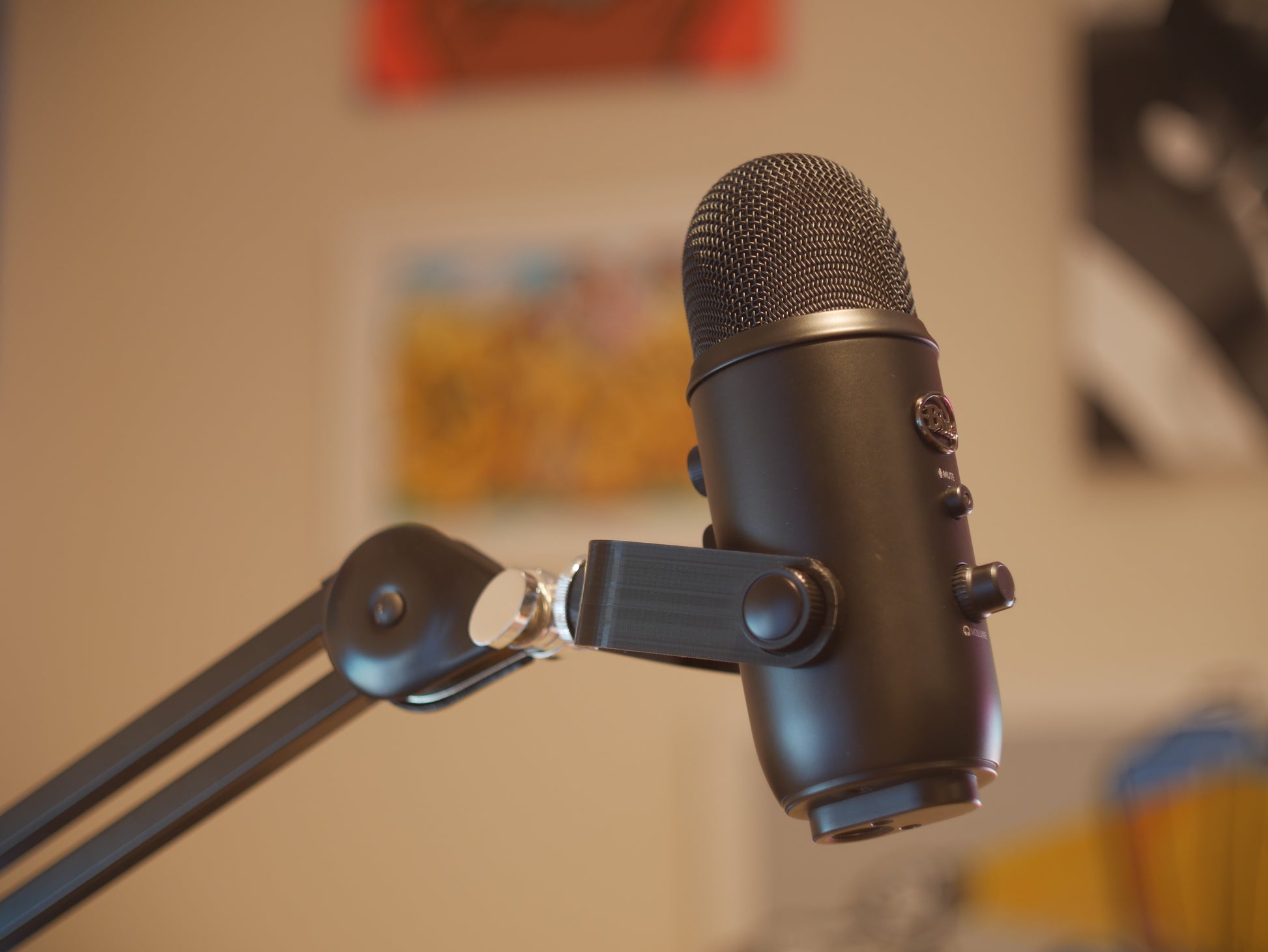 A black microphone mount attached to a boom arm and holding a Blue Yeti microphone.