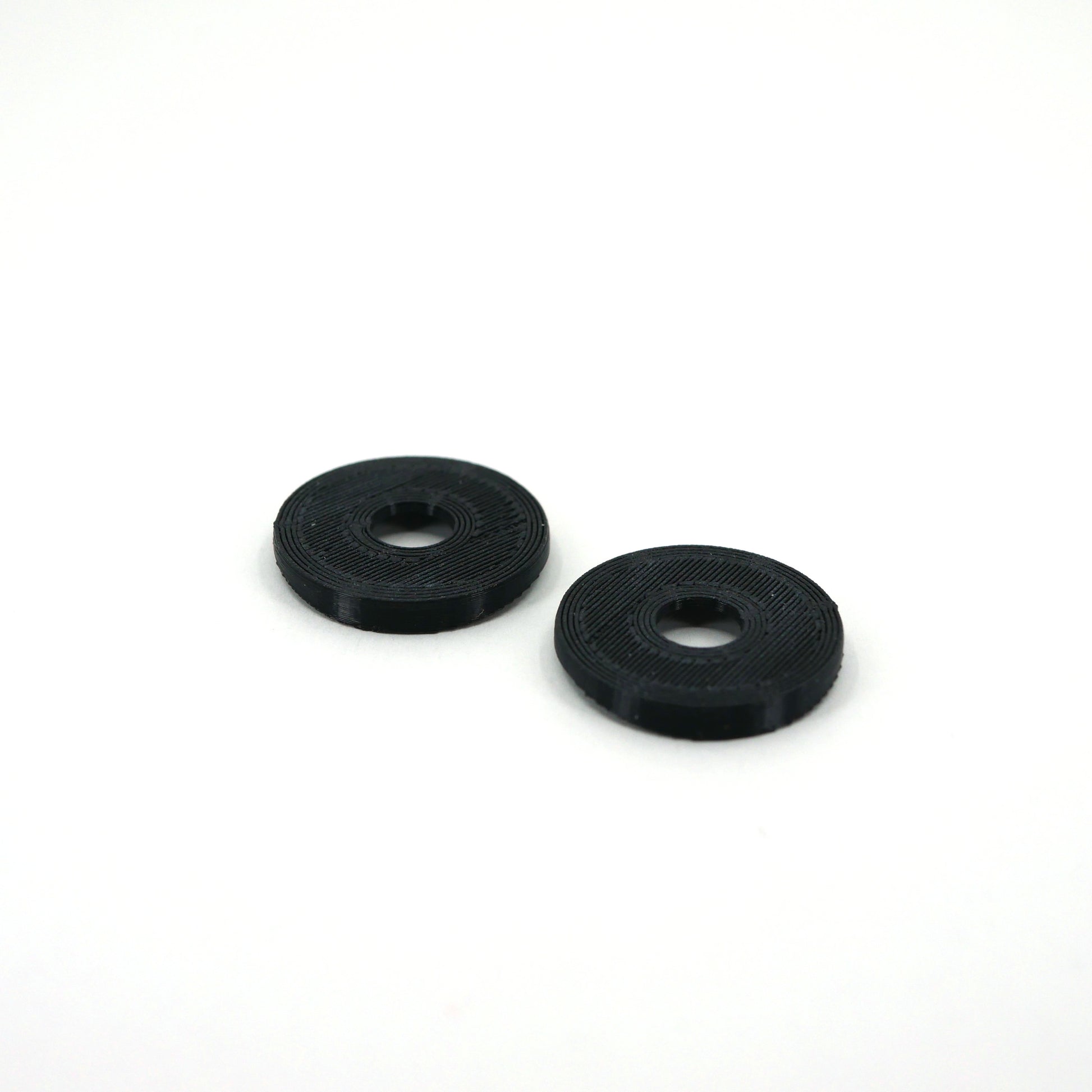 The bottom of two black microphone washers for the Blue Yeti microphone.