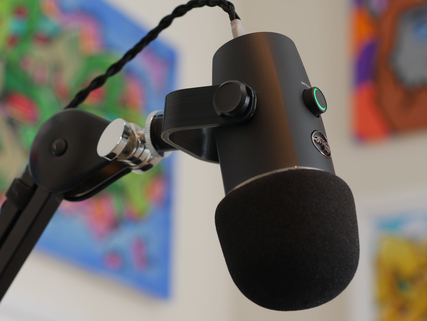 A black microphone mount attached to a boom arm and holding a Blue Yeti Nano microphone.