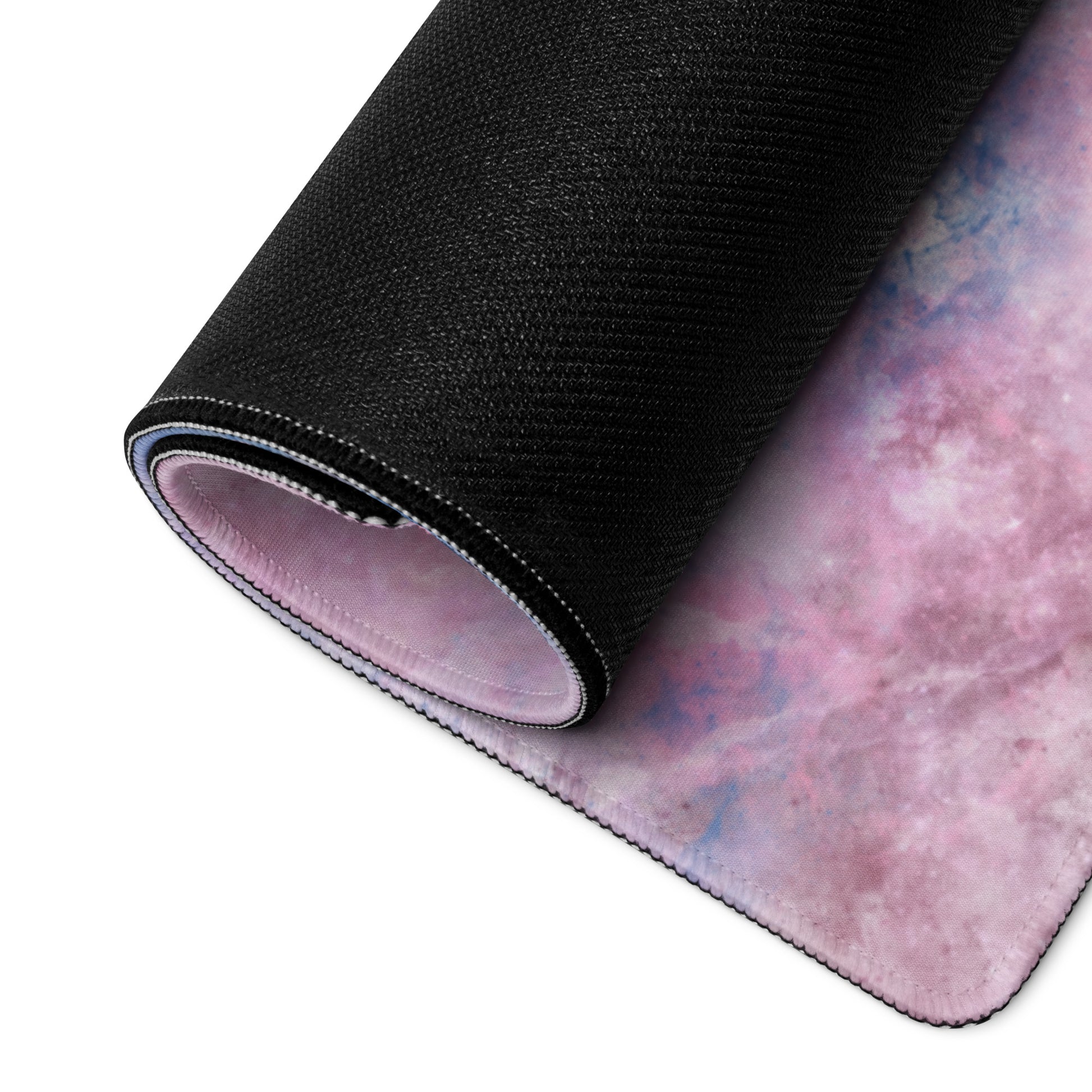 A pink, blue, and white gaming desk pad with the quote It's me, hi! I'm the problem, it's me. The desk pad is rolled up.