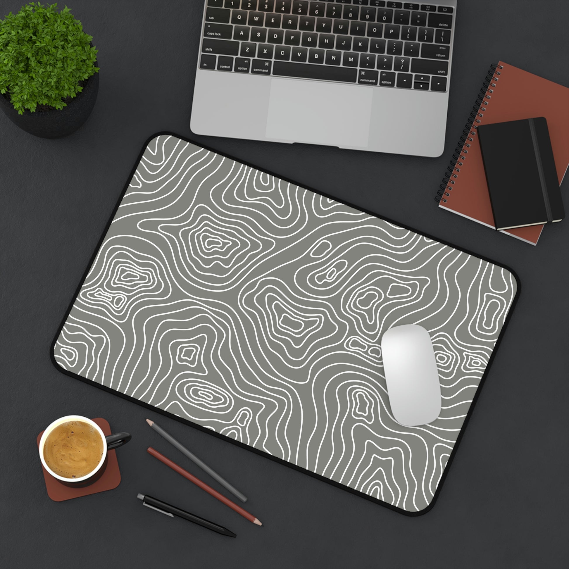 A 12" x 18" gray desk mat with white topographic lines sitting at an angle. A mouse sits on top of it.