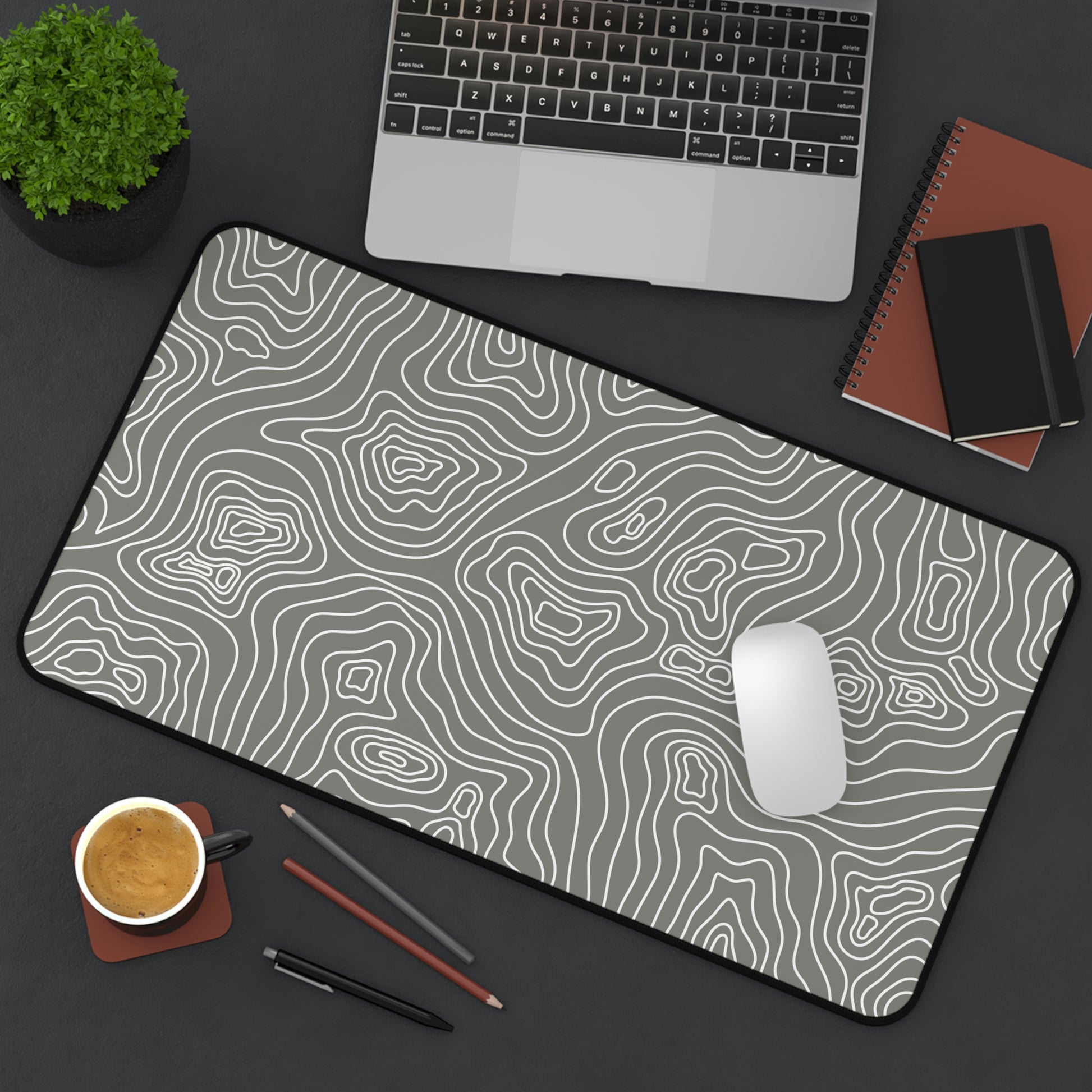 A 12" x 22" gray desk mat with white topographic lines sitting at an angle. A mouse sits on top of it.