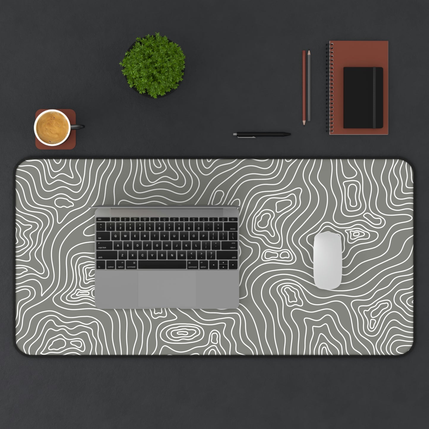 A 31" x 15.5" gray desk mat with white topographic lines. A laptop and mouse sit on top of it.