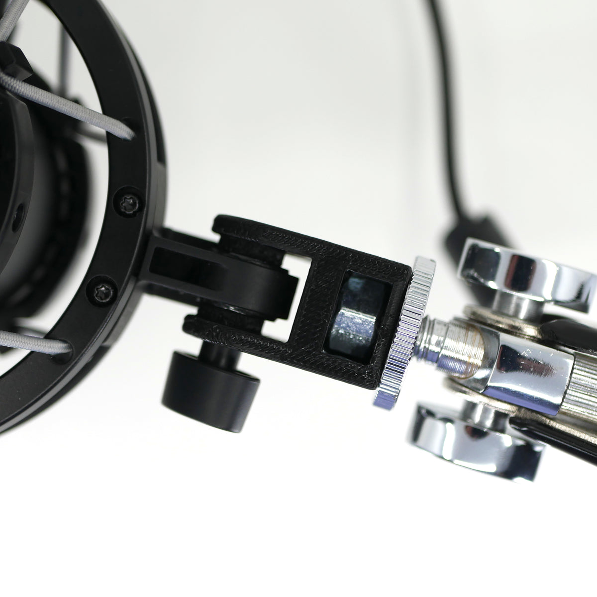 The top of a HyperX QuadCast microphone mount adapter attached to a boom arm and holding the HyperX QuadCast microphone.