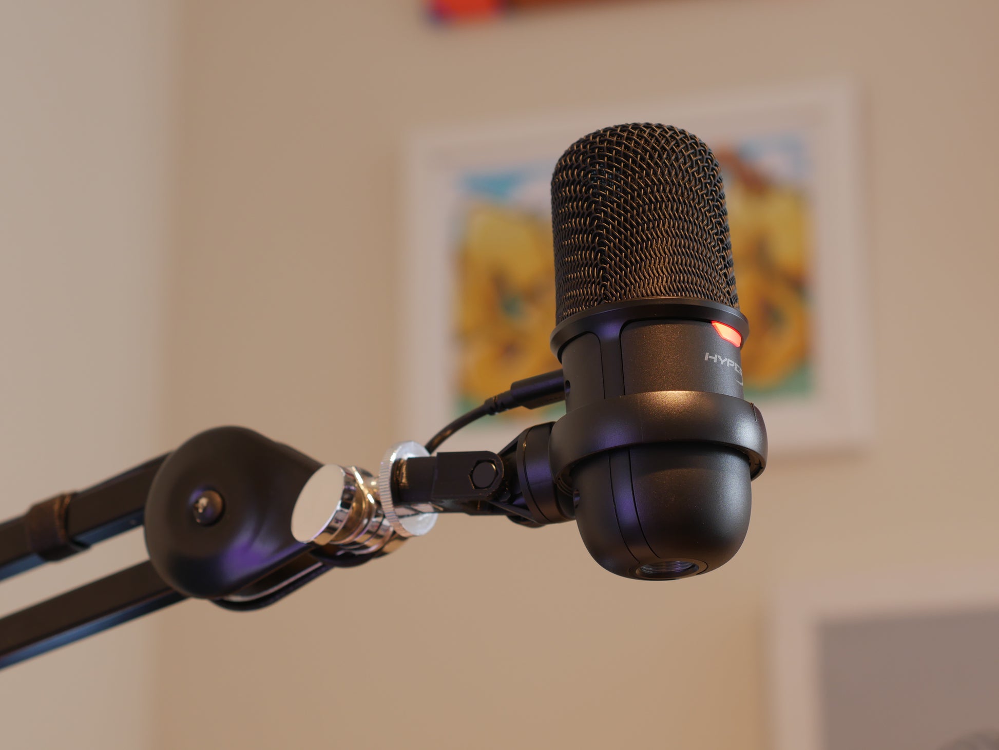 A black HyperX SoloCast microphone mount adapter attached to a boom arm and holding the HyperX SoloCast microphone.