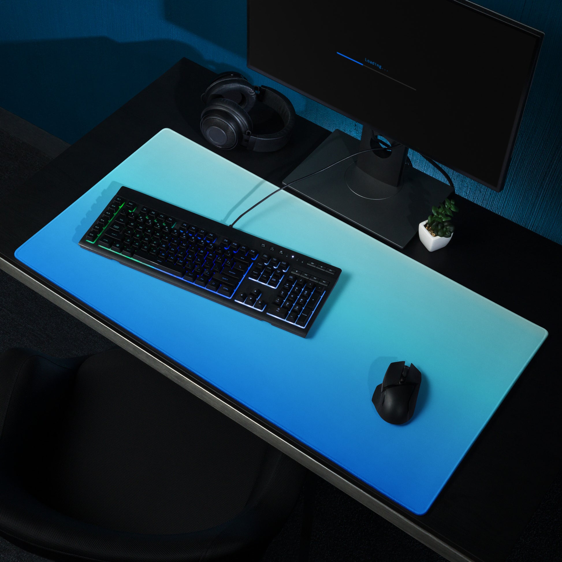 A 36" x 18" gaming desk pad with dark blue at the bottom and light blue at the top. It sits on a desk with a monitor, keyboard, and mouse.