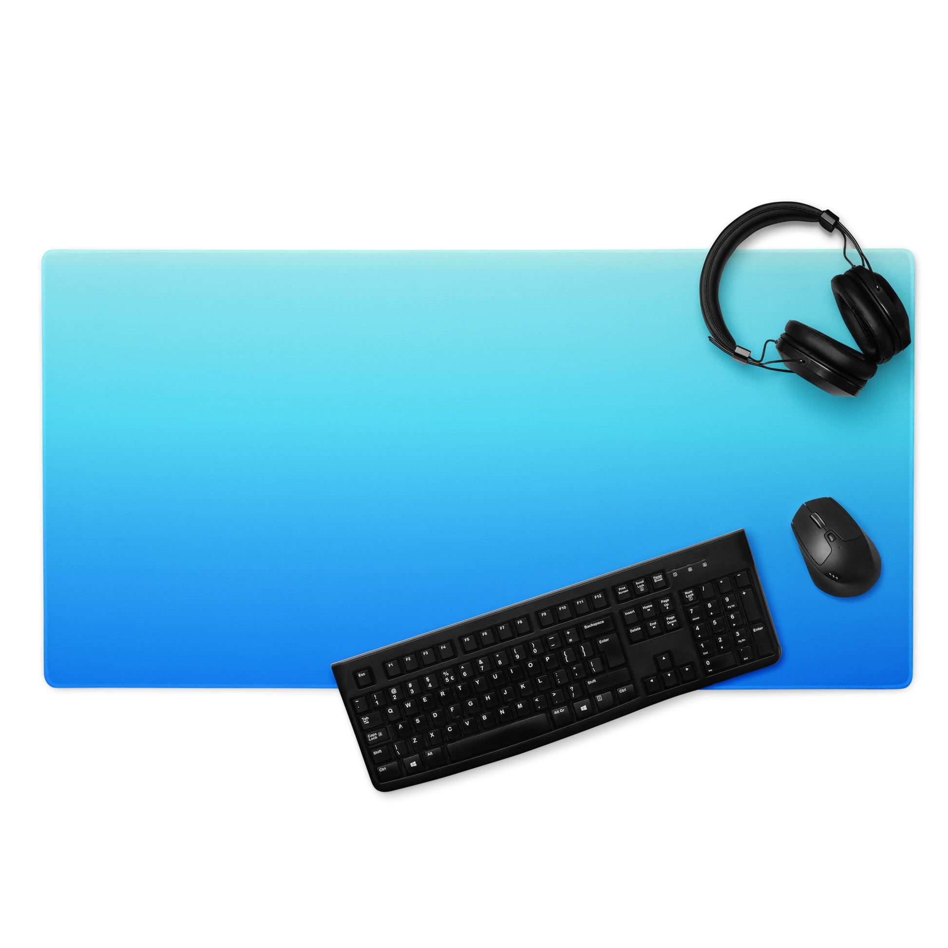 A 36" x 18" gaming desk pad with dark blue at the bottom and light blue at the top. A keyboard, headphones, and mouse sit on top of it.