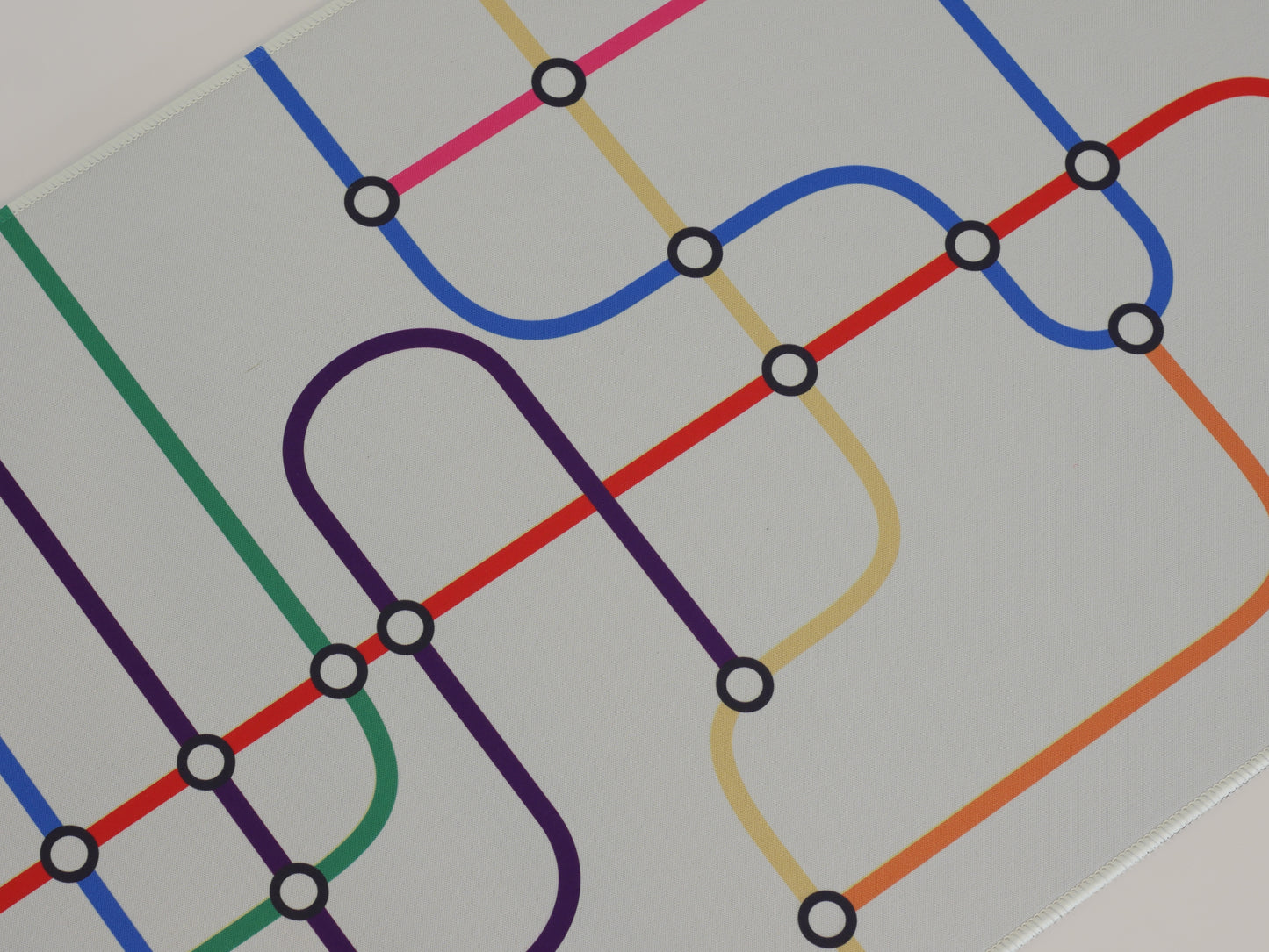 The middle of the subway transit desk mat. The desk mat has a white background and colorful lines.