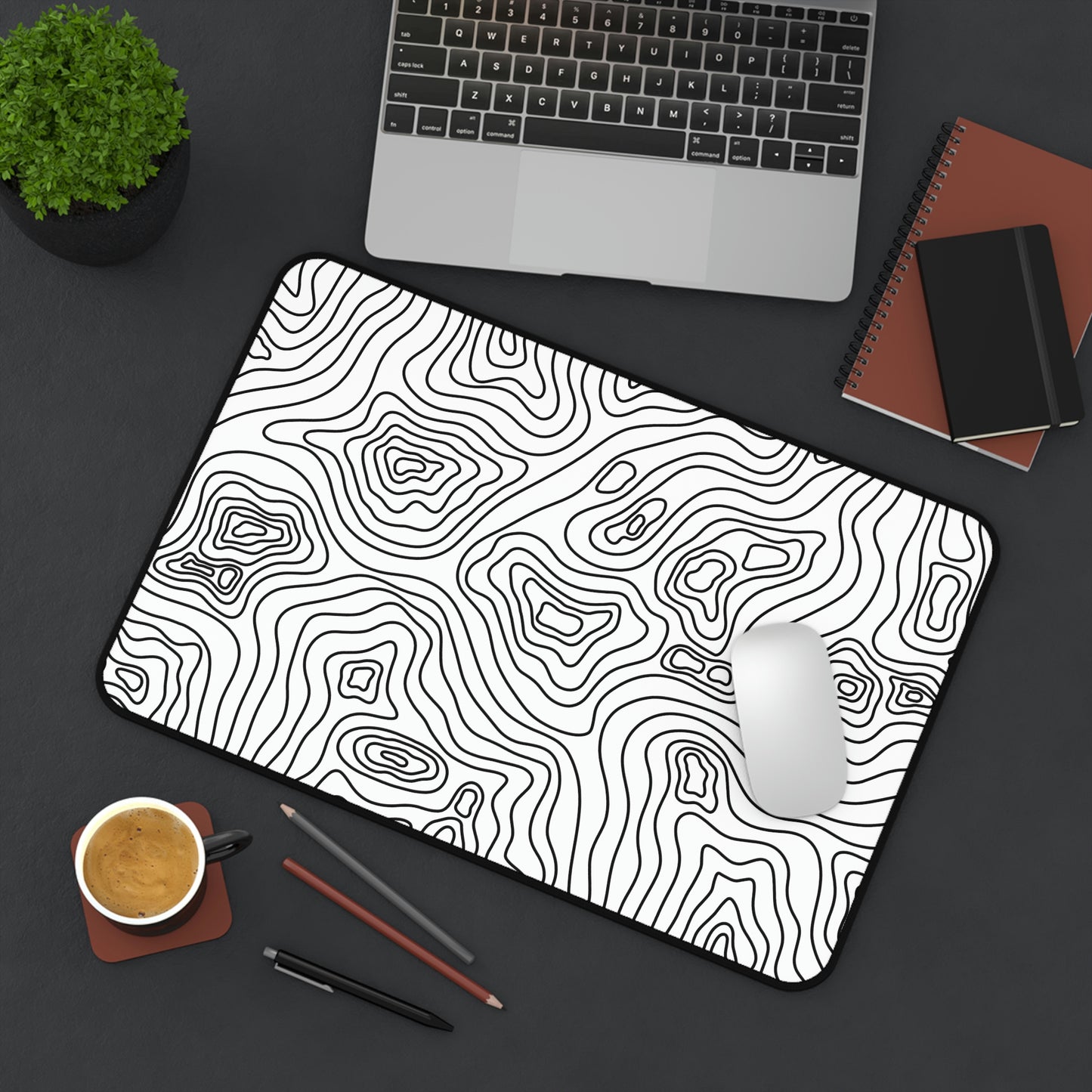 A 12" x 18" white desk mat with black topographic lines sitting at an angle. A mouse sits on top of it.