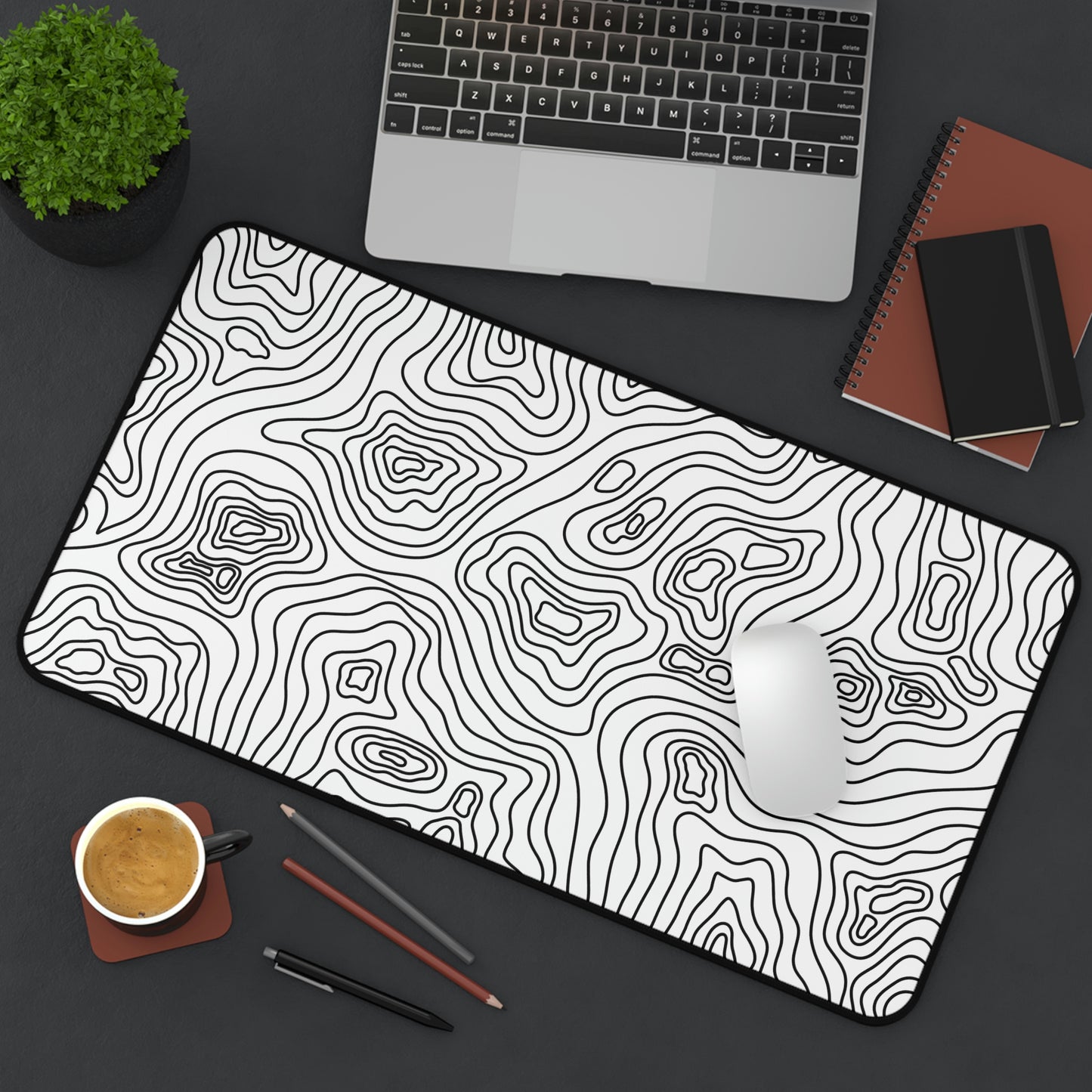 A 12" x 22" white desk mat with black topographic lines sitting at an angle. A mouse sits on top of it.