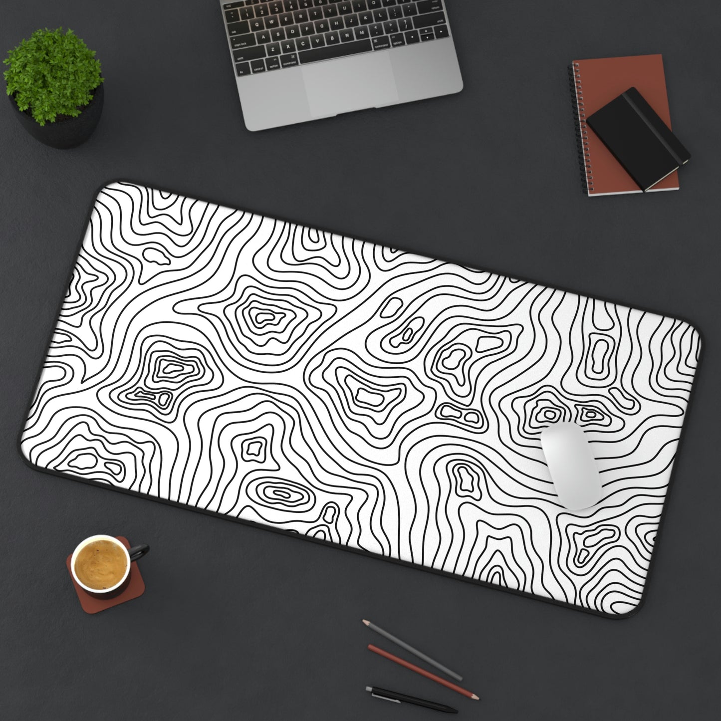 A 31" x 15.5" white desk mat with black topographic lines sits at an angle. A mouse sits on top of it.