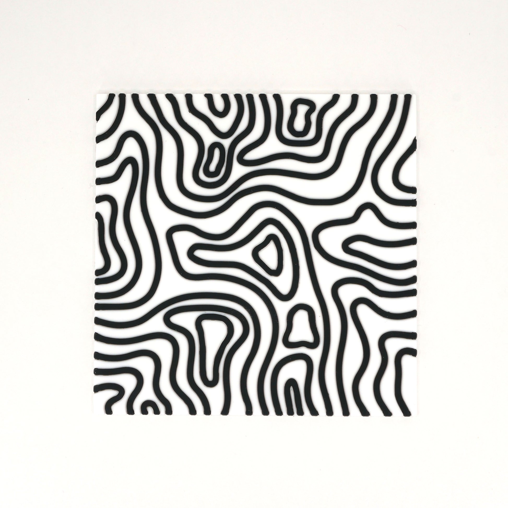 A square white topographic PVC rubber coaster with black lines.