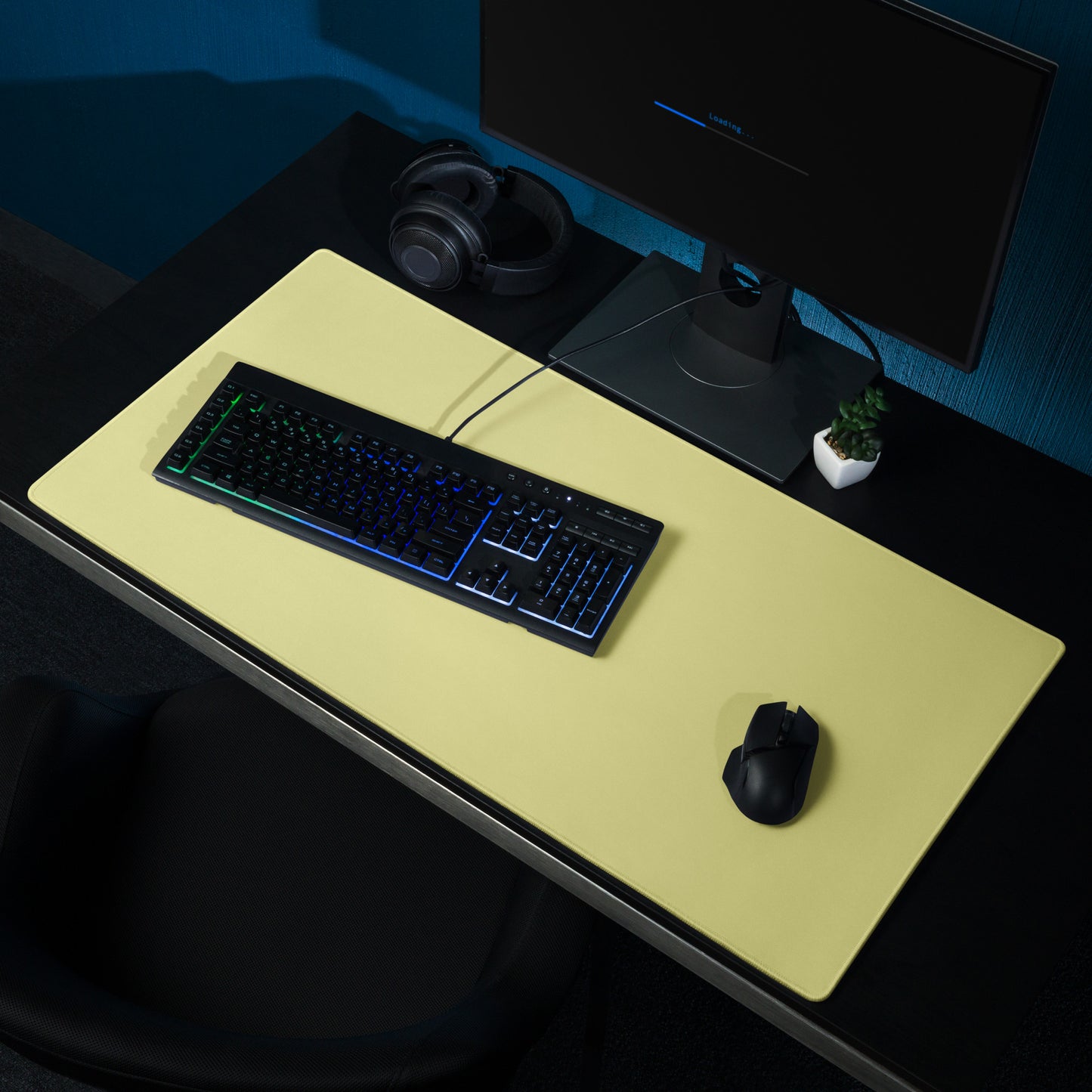 A 36" x 18" yellow gaming desk pad sitting on a black desk with a monitor, keyboard, and mouse.